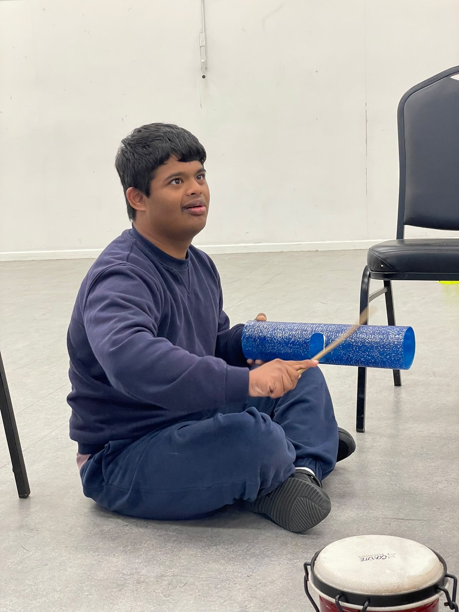 A disabled boy playing a musical instrument as part of a Capoeira class