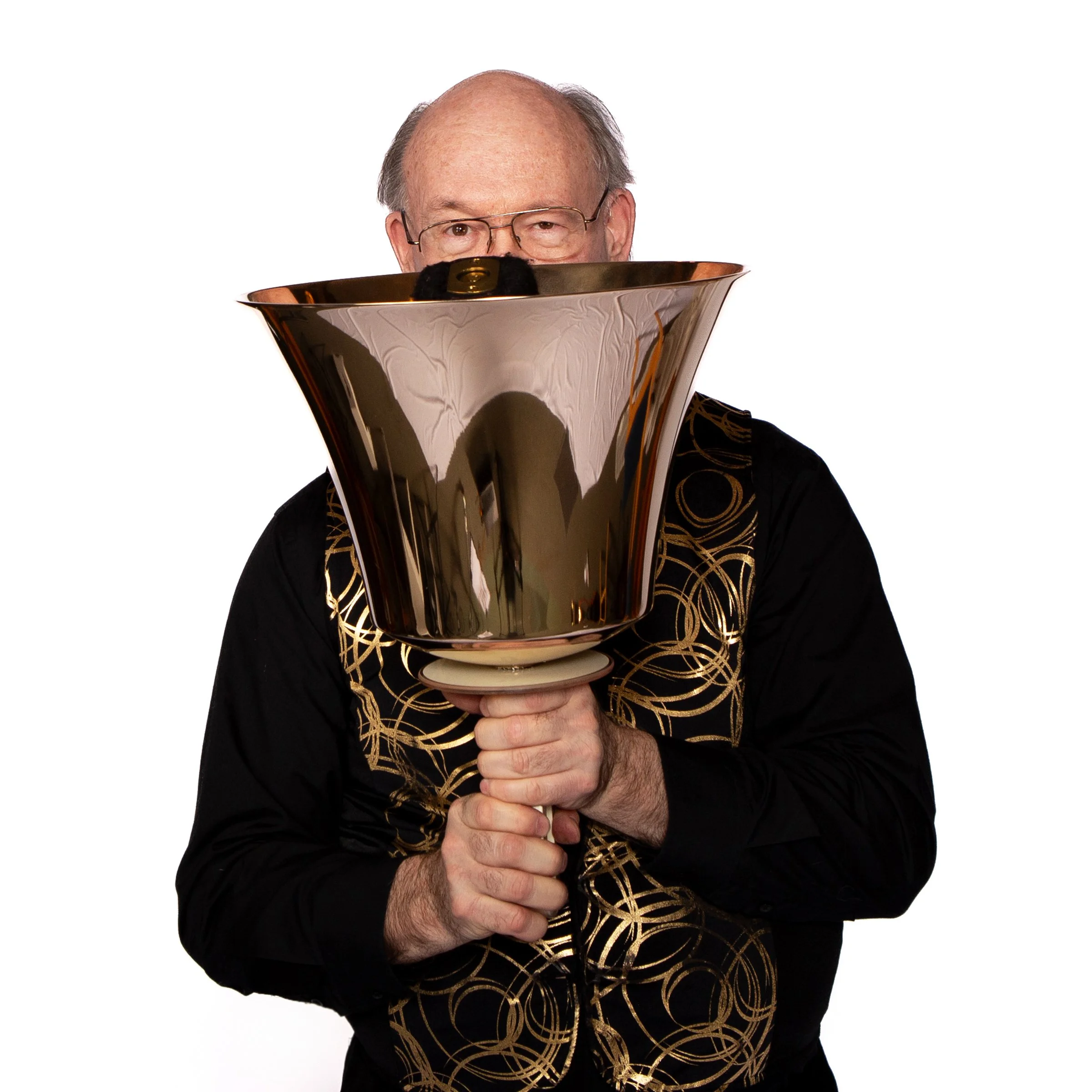 A man with glasses holding a large handbell with both hands.