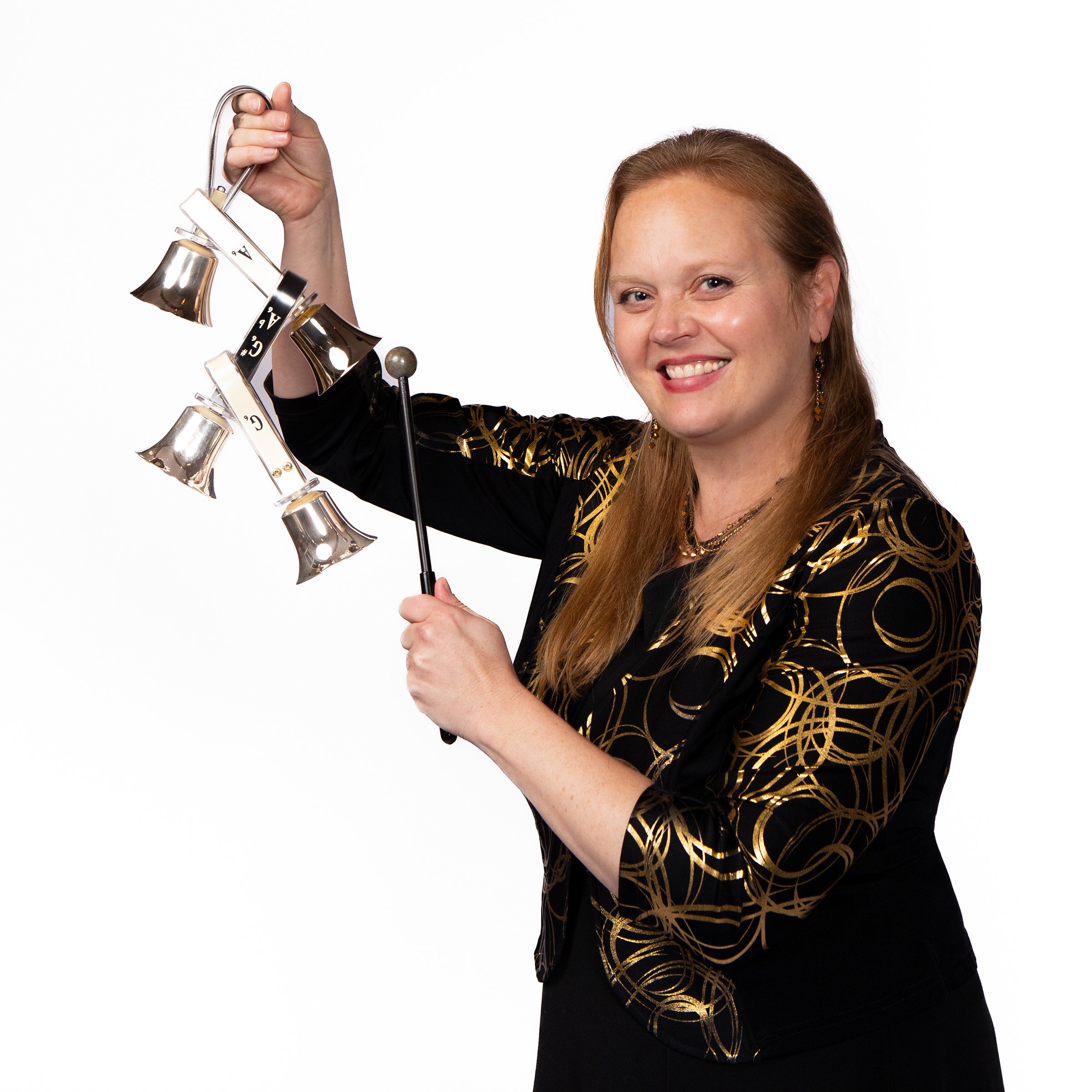 Woman with long red hair smiling and holding handbells.