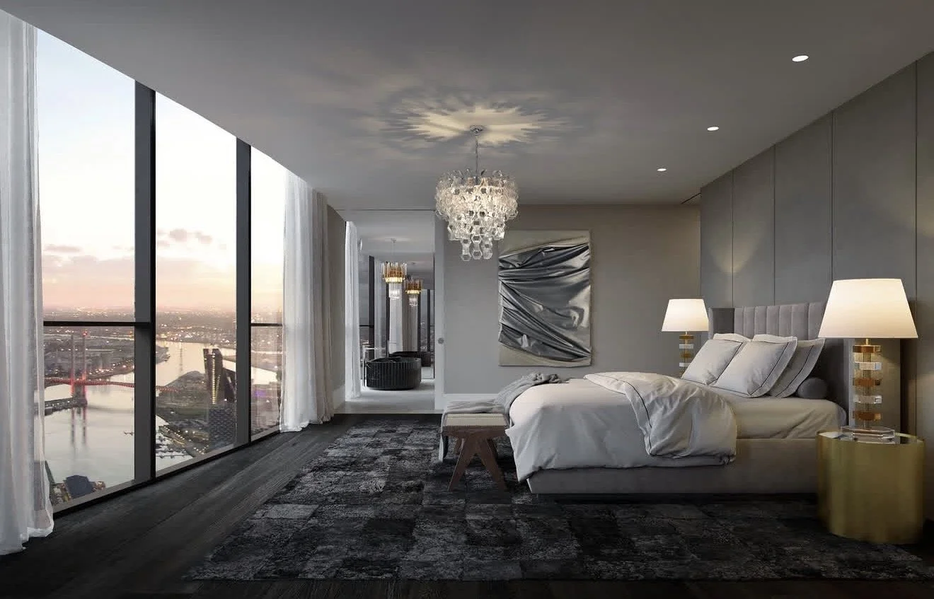 Modern luxury bedroom with large, thin, grey, curly rug, chandelier, floor-to-ceiling windows overlooking a waterfront city at sunset, creating a calm mood.