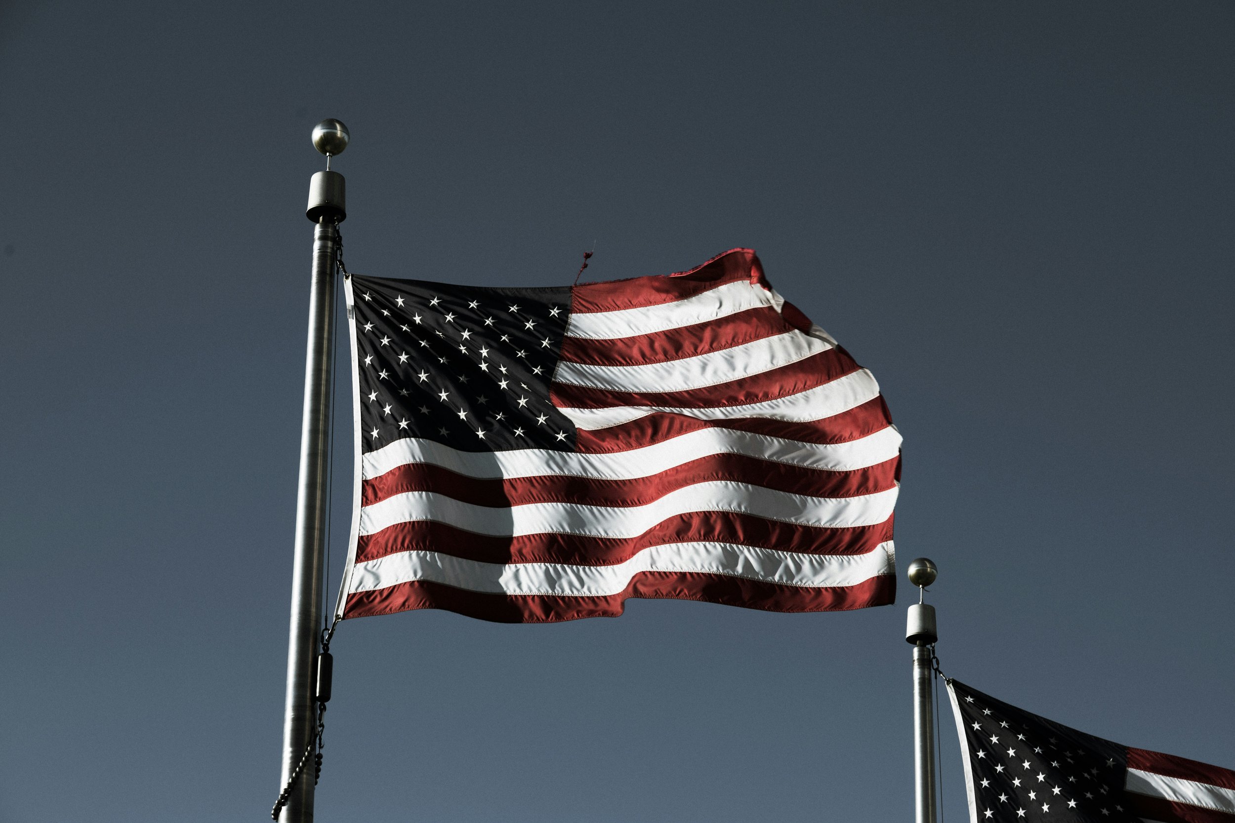 American flag flying on a flagpole against a dark sky.