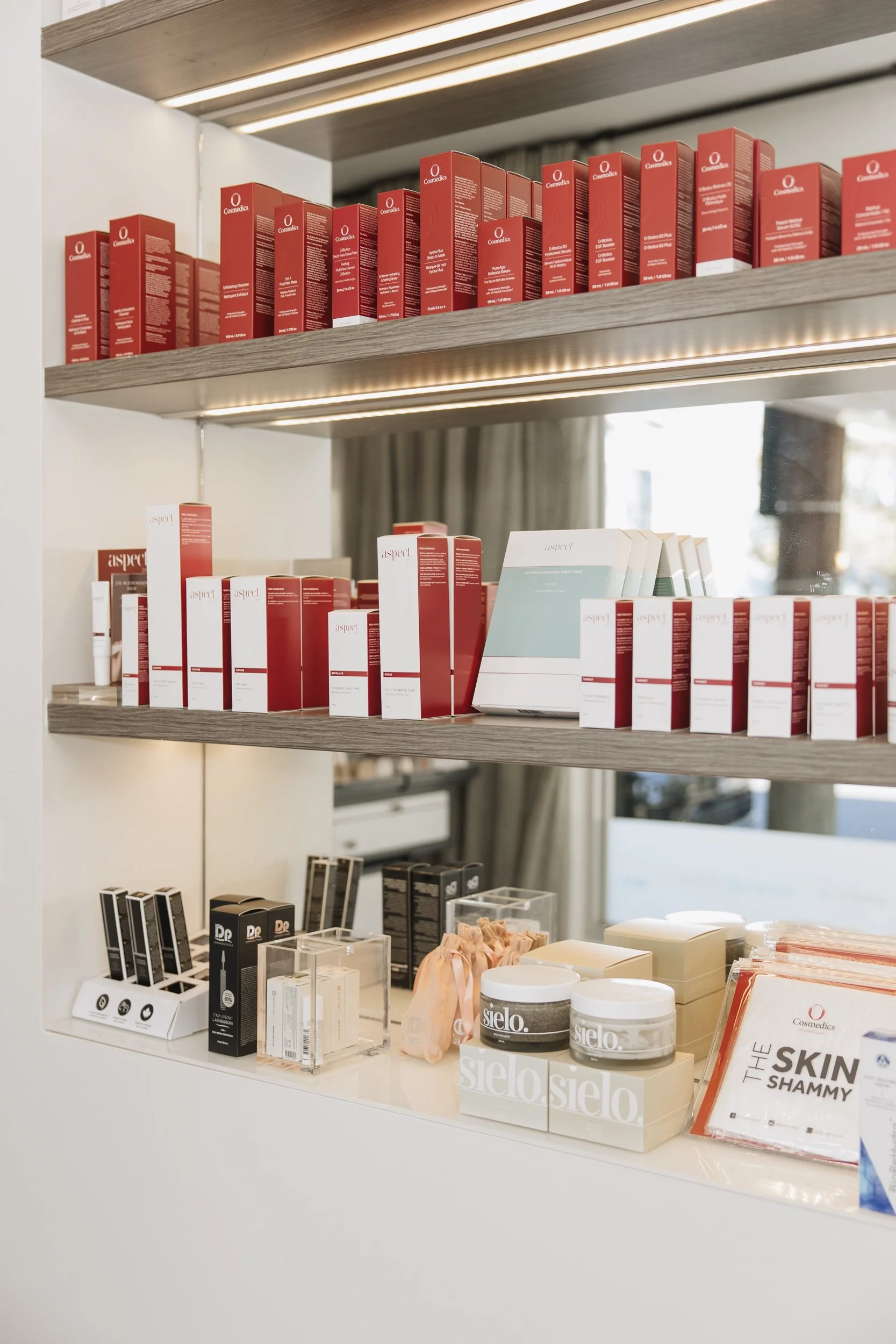 Display of skincare and beauty products on white shelves with wooden accents, including boxes, jars, and informational signage.