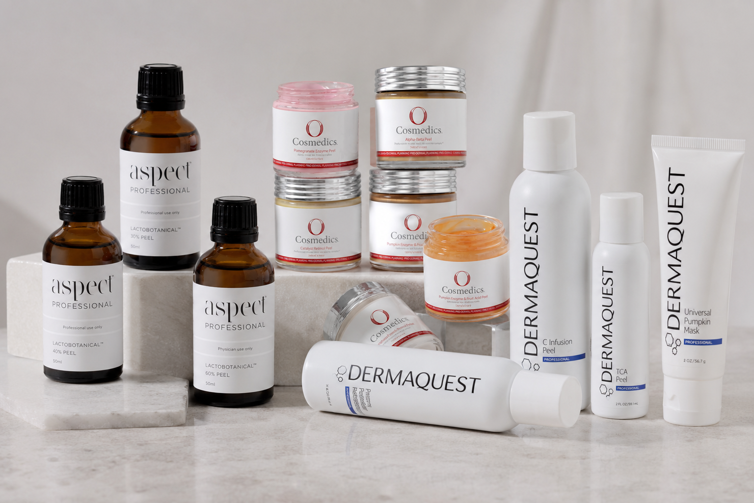 Skincare products including Aspect Professional, Cosmedics, and Dermaquest brands on display; includes jars, bottles, and a tube, some with labels indicating peel, enzyme, mask, and infusion treatments, arranged on stone and marble surfaces.