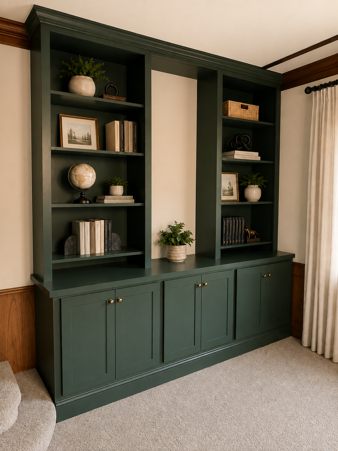 Green built-in bookshelf with decorative items, books, plants, and framed pictures in a cozy living room.