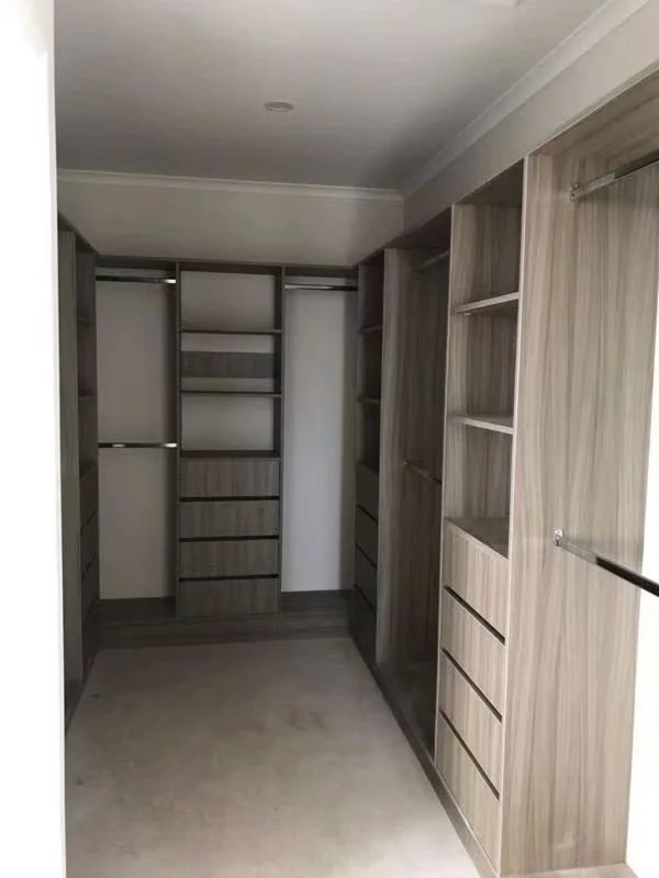 Empty walk-in closet with built-in wooden shelving, drawers, and hanging rods