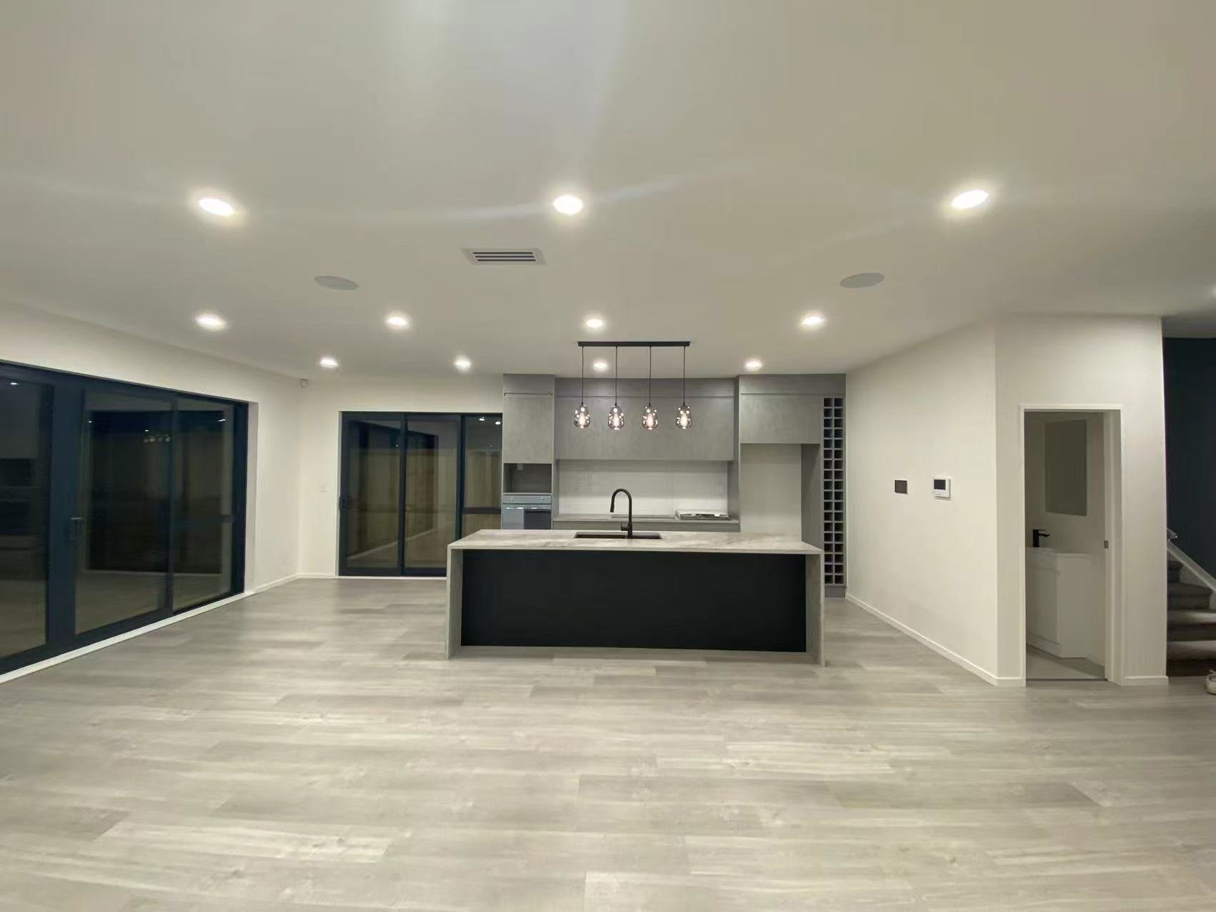Modern, spacious kitchen with an island, pendant lights, and large sliding glass doors.