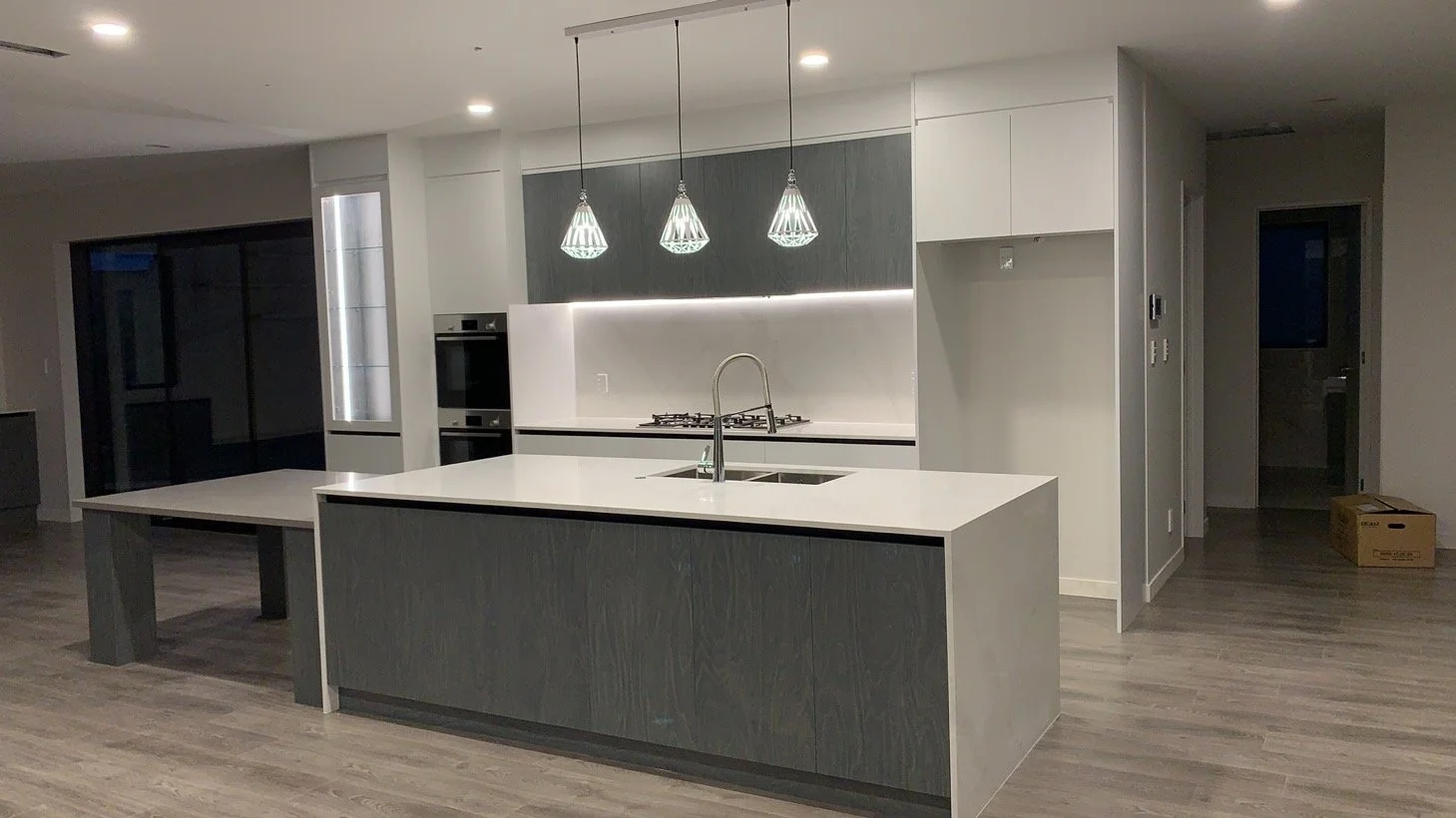 Modern kitchen with island, pendant lighting, built-in oven, and minimal decor.