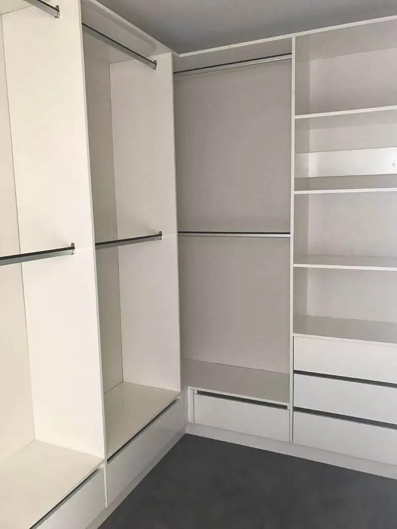 Empty white walk-in closet with shelves, drawers, and hanging rods.