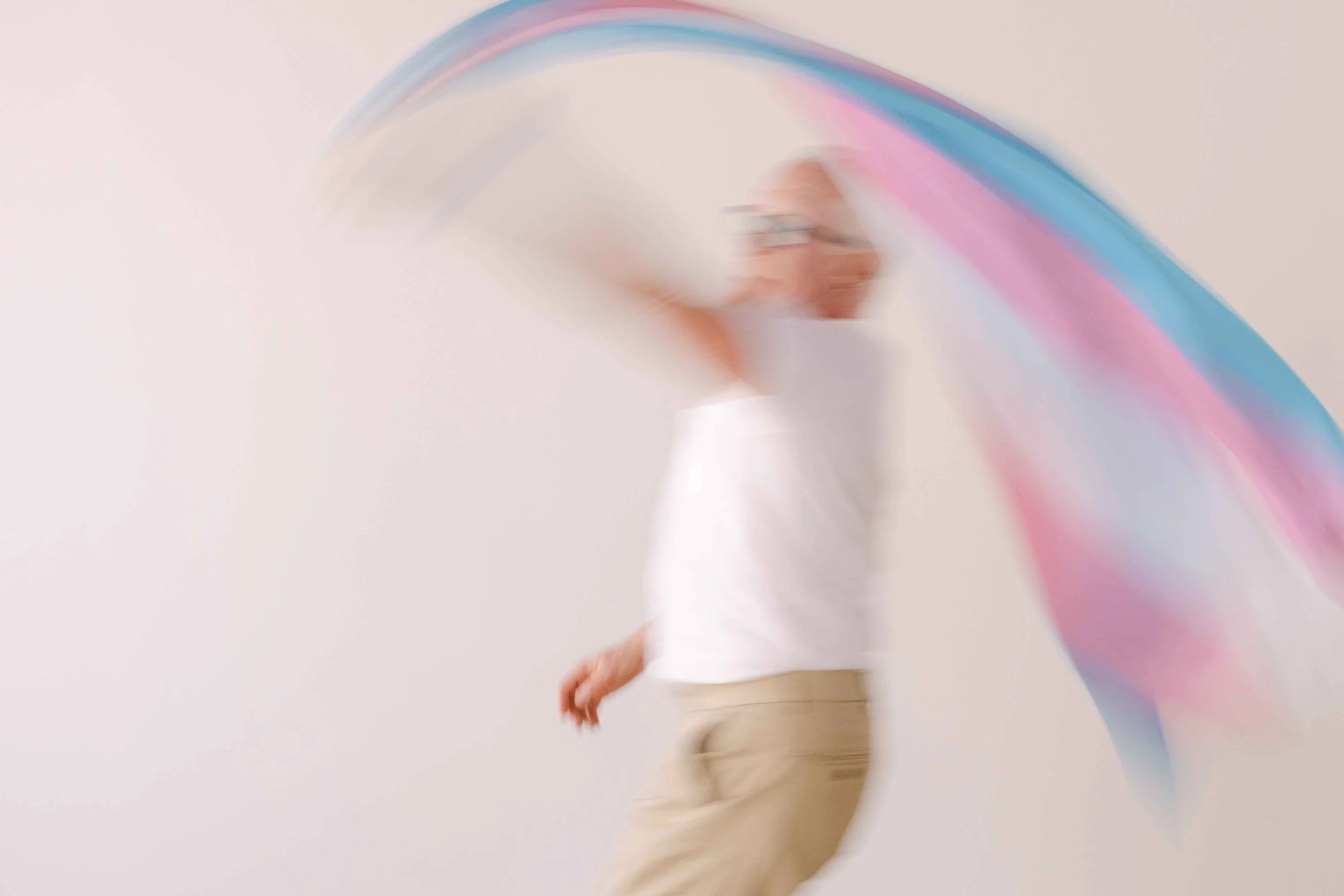 Blurry image of a person in motion, with rainbow light streaks and a light-colored background.
