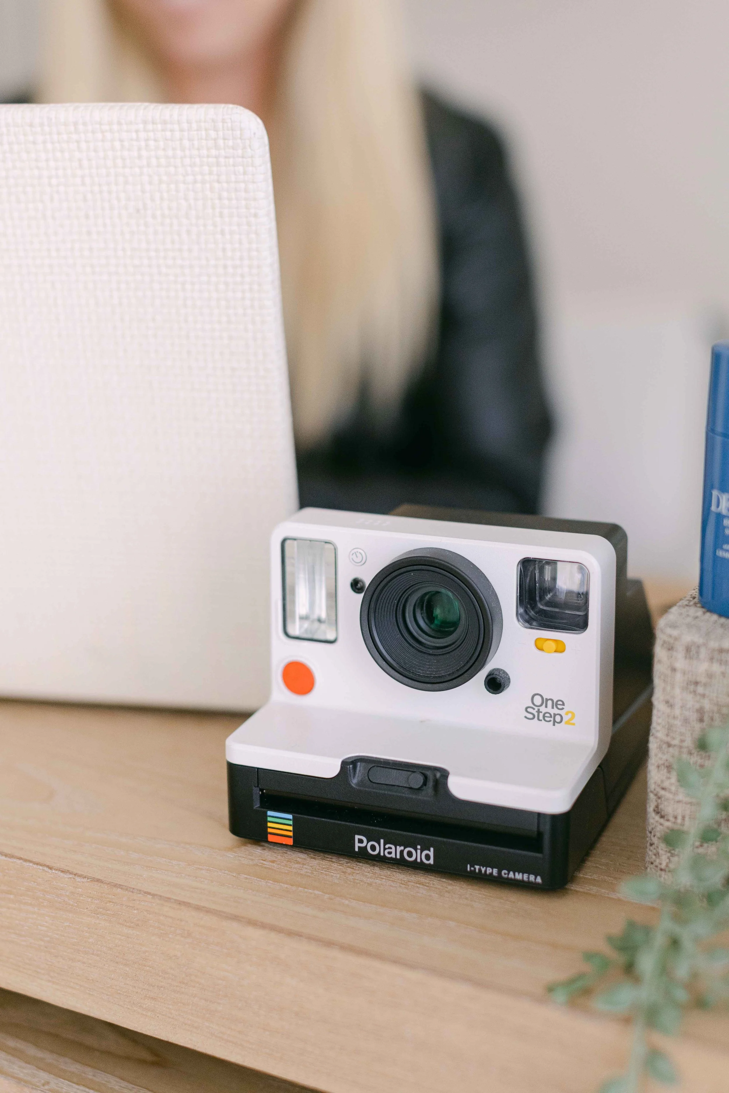 A Polaroid I-Type camera placed on a wooden table with a blurred background.