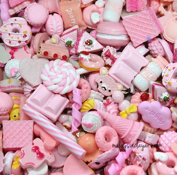 A collection of pink and pastel-colored candies, chocolates, and sweets, including marshmallows, lollipops, and cookies.