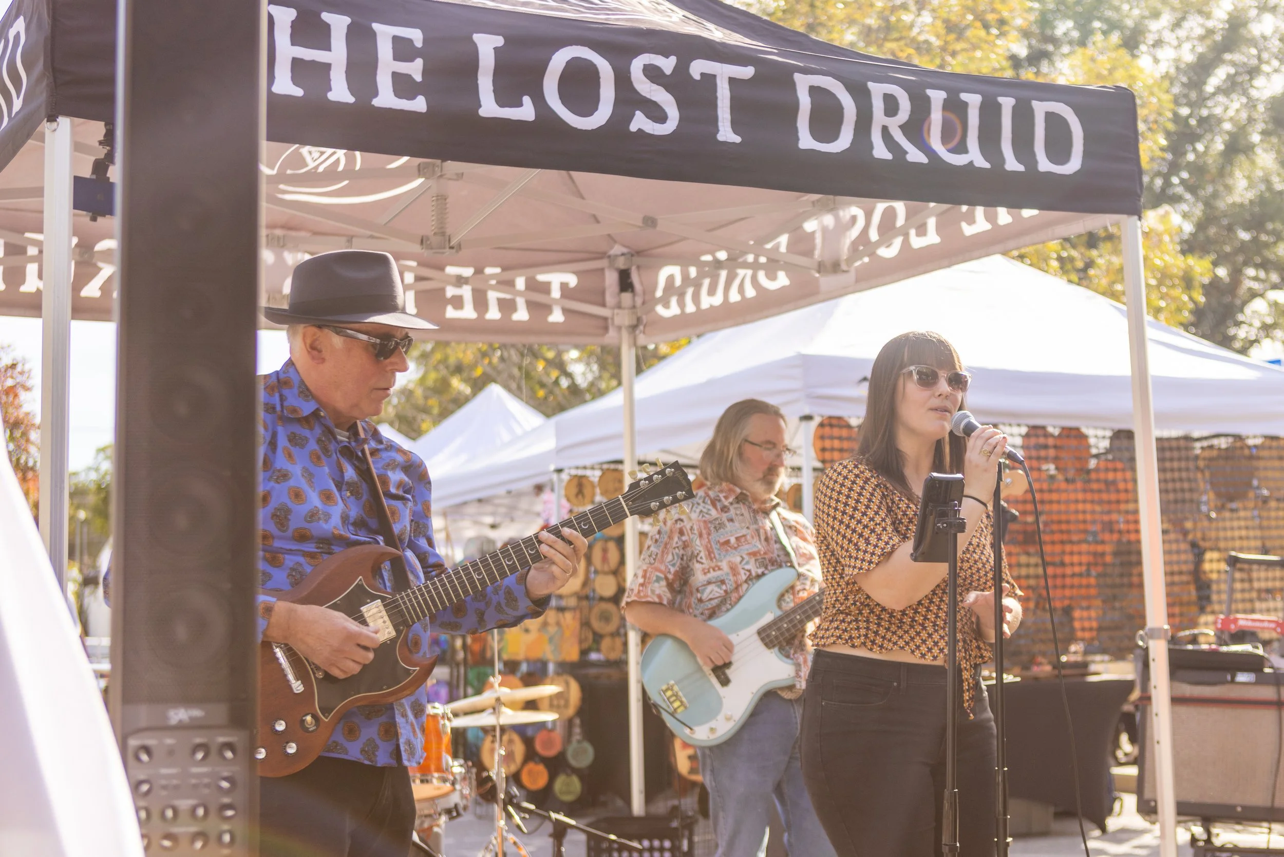 A group of musicians performing outdoors under a tent that has 