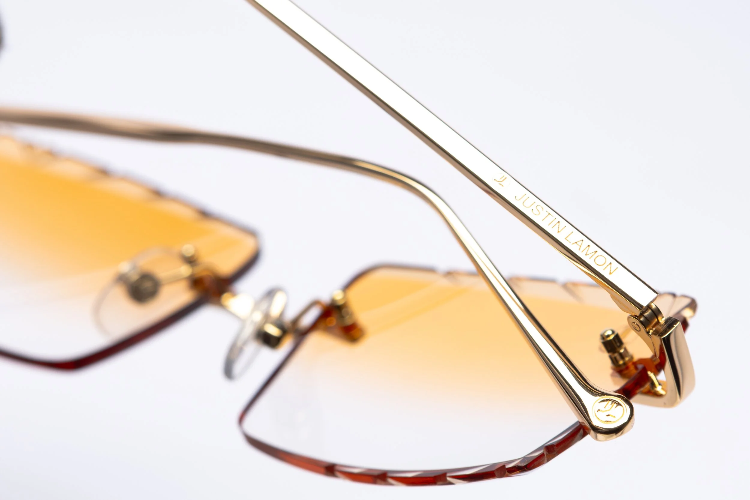 Gold-colored sunglasses with yellow lenses and a gold-branded arm that reads 'JUSTIN LAMON' on a white background.