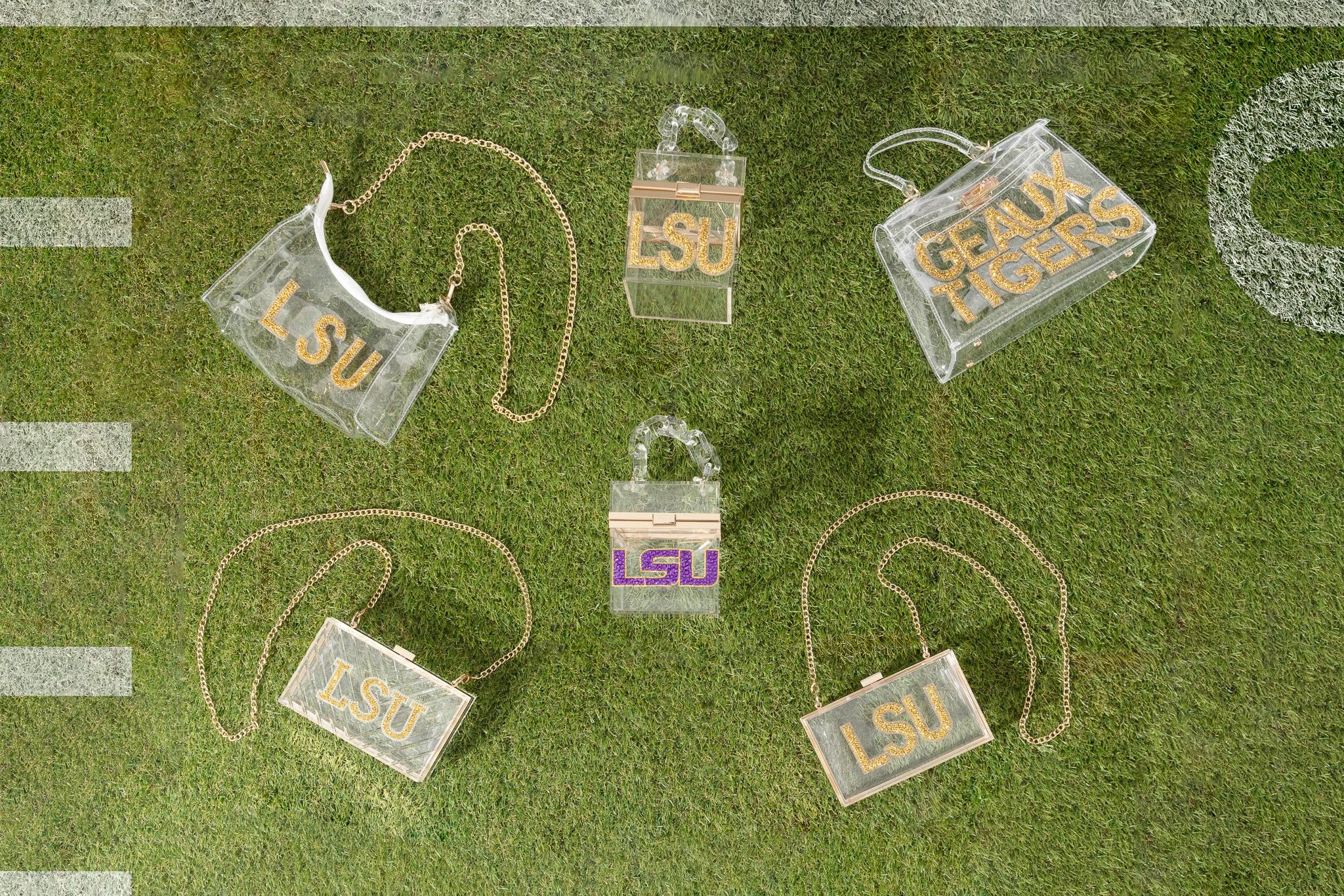 Various acrylic jewelry pieces with LSU Tigers logos and text, displayed on green grass.