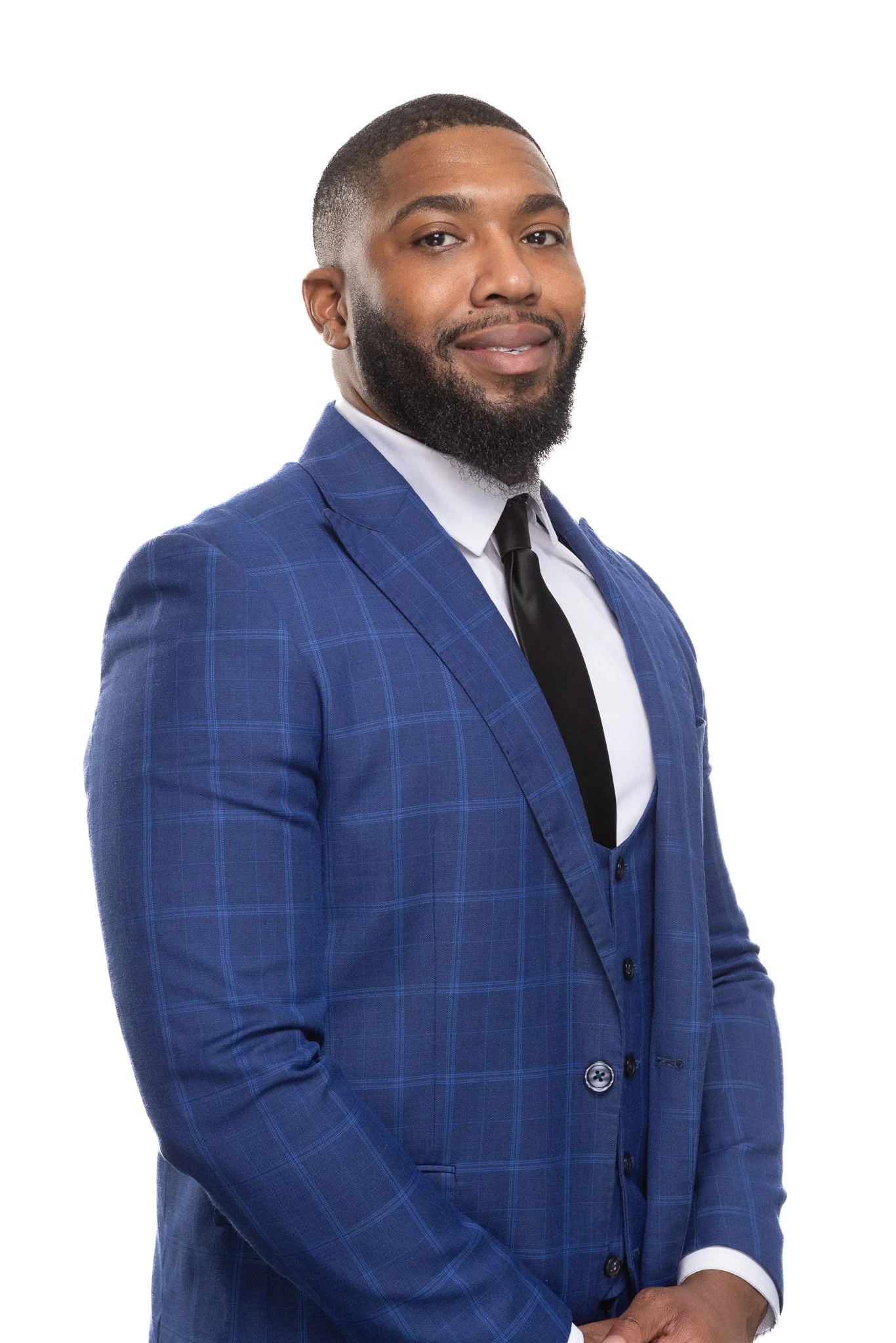 A confident African American man in a blue checkered suit, white shirt, and black tie, standing against a plain white background.