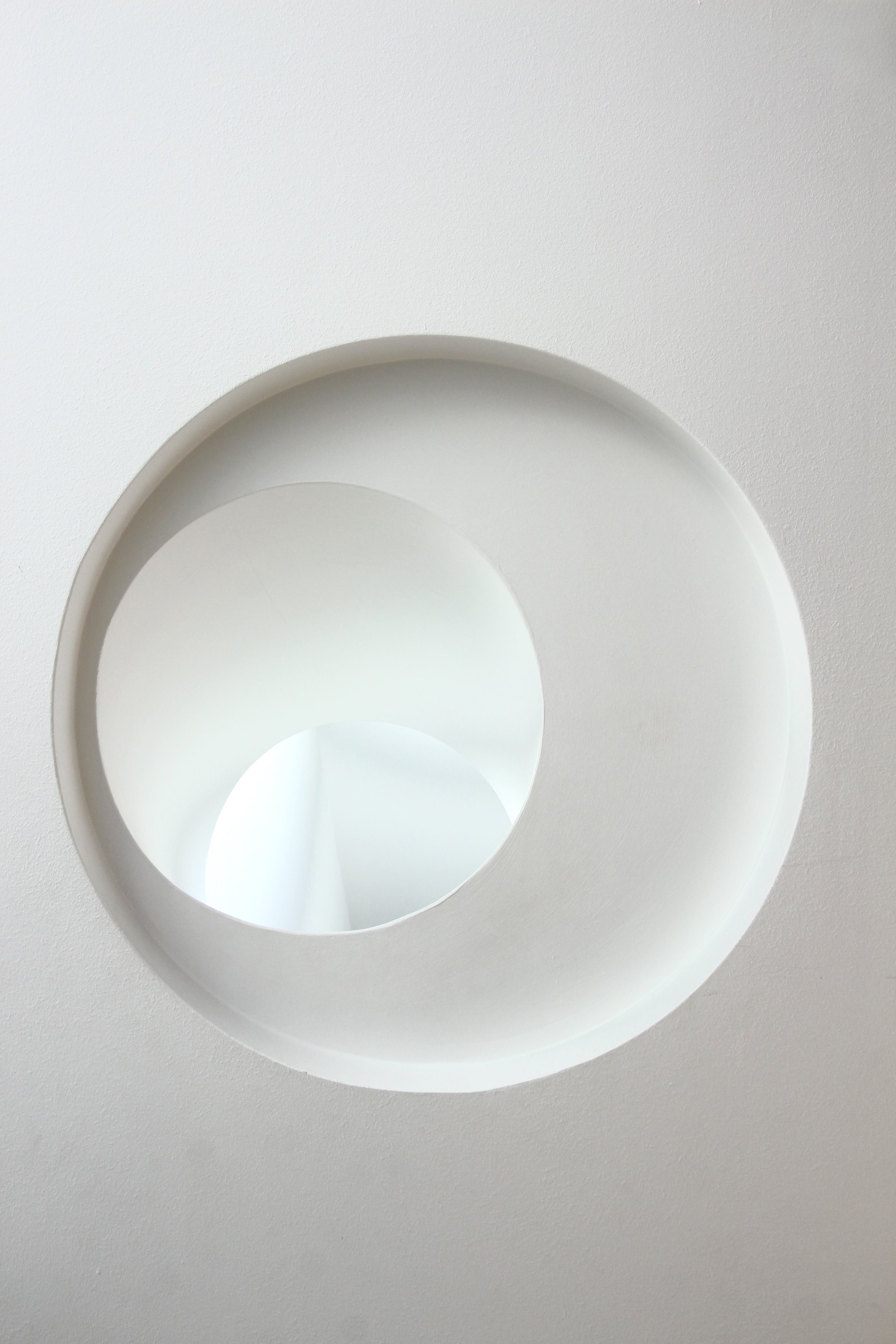 Close-up image of a white circular architectural feature or sculpture with multiple concentric circles and hollow centers on a white background.