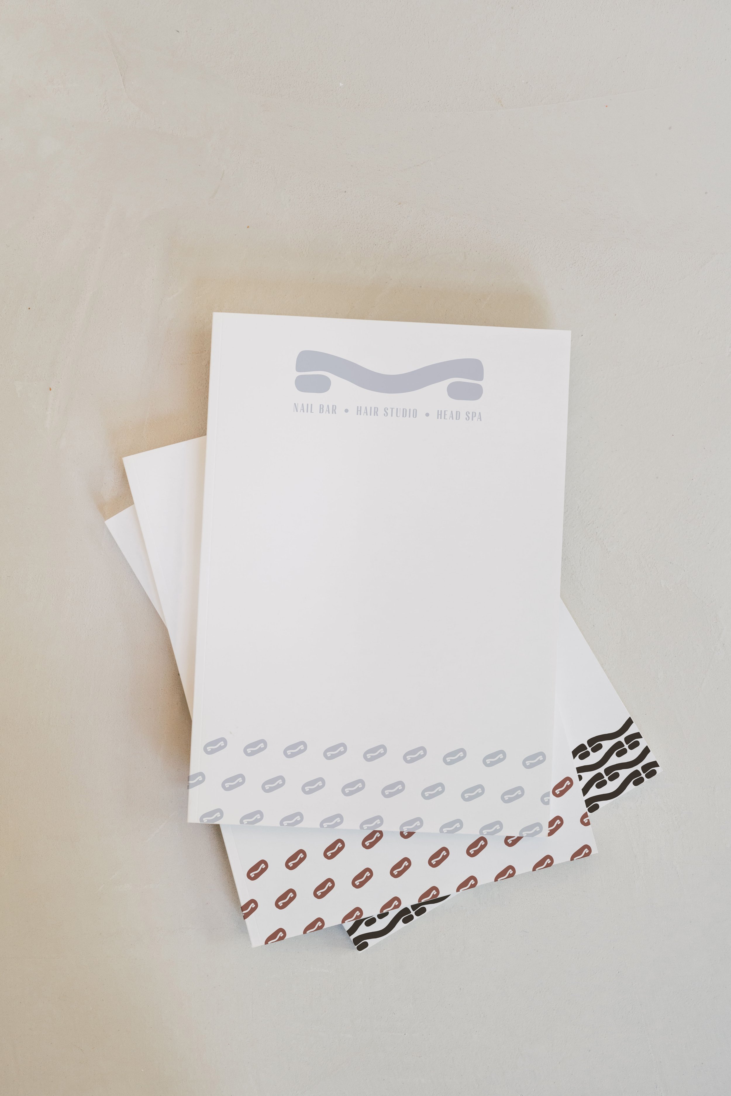 Set of papers with letterhead with various black, brown, white, and gray abstract patterns on a light-colored surface.