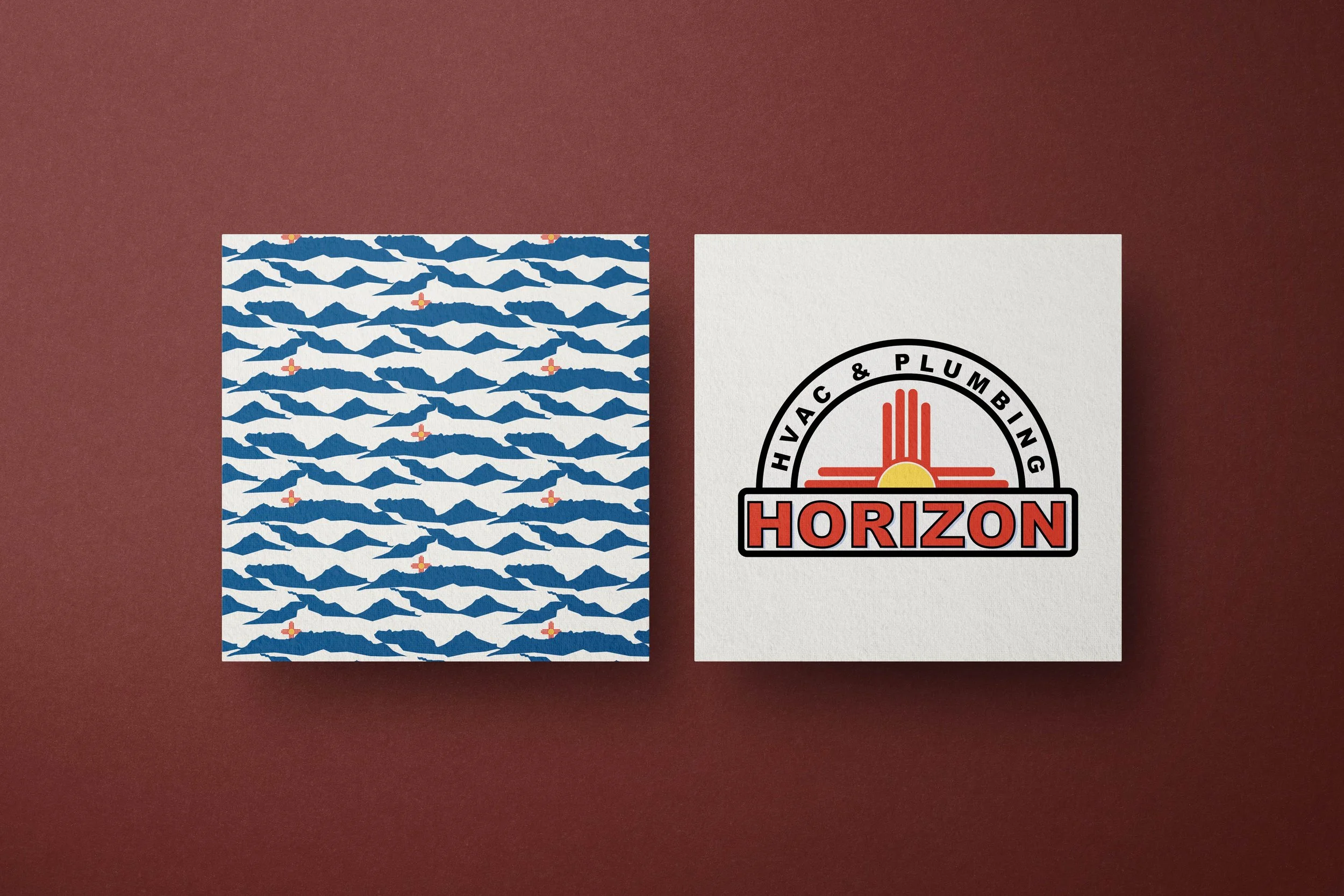 Two pieces of paper, one with a pattern of blue mountain shapes and small red and yellow crossover symbols, and the other with a black and red logo that reads 'Horizon' and includes a sun and circle design, are placed on a dark red background.