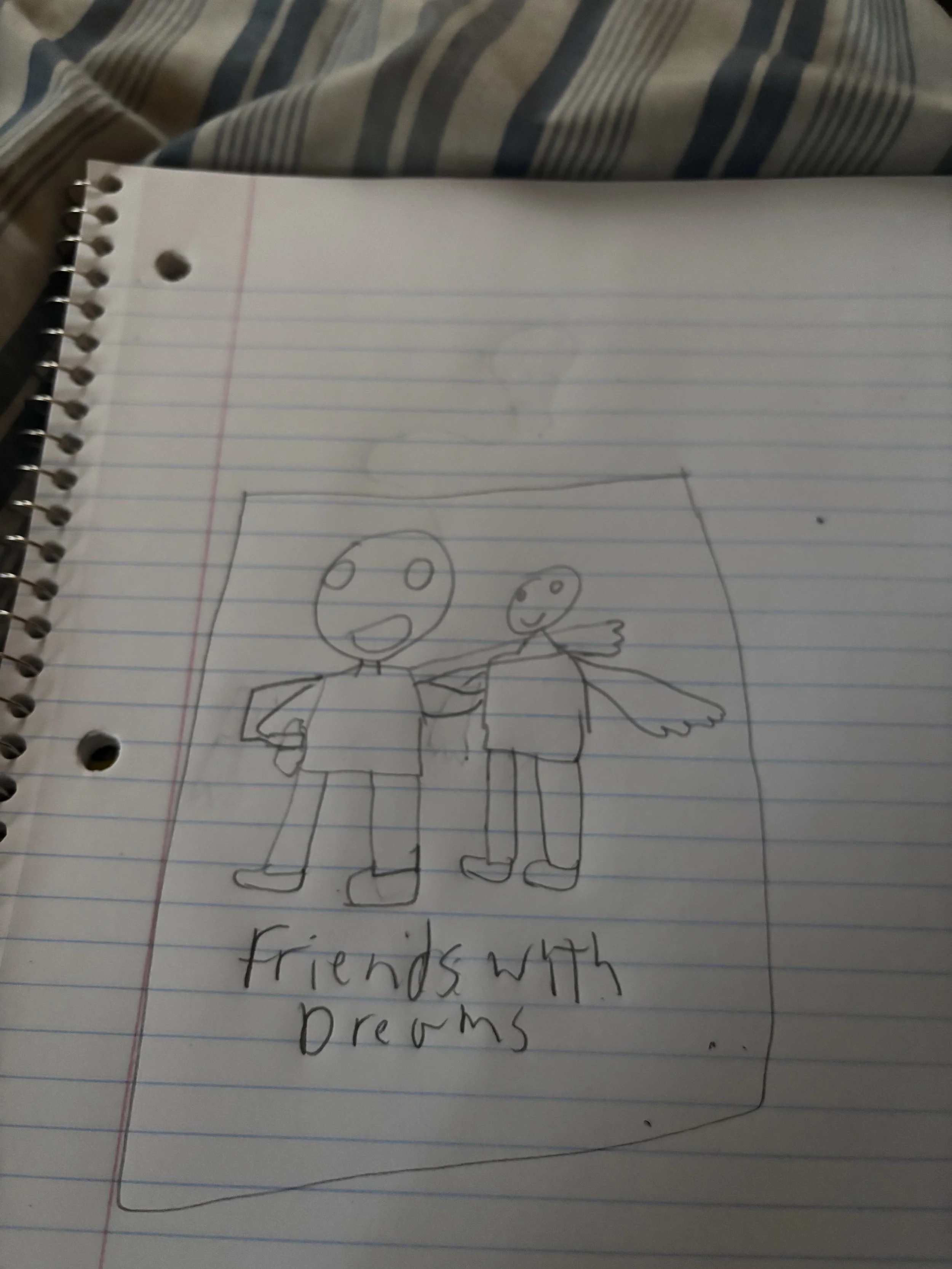 A hand-drawn picture of two figures with large round heads and simple facial features. One figure has a large open mouth and is raising an arm, while the other is smiling and has wings. The drawing is on a lined notebook paper. Below the illustration, there is handwritten text that says "friends with dreams."