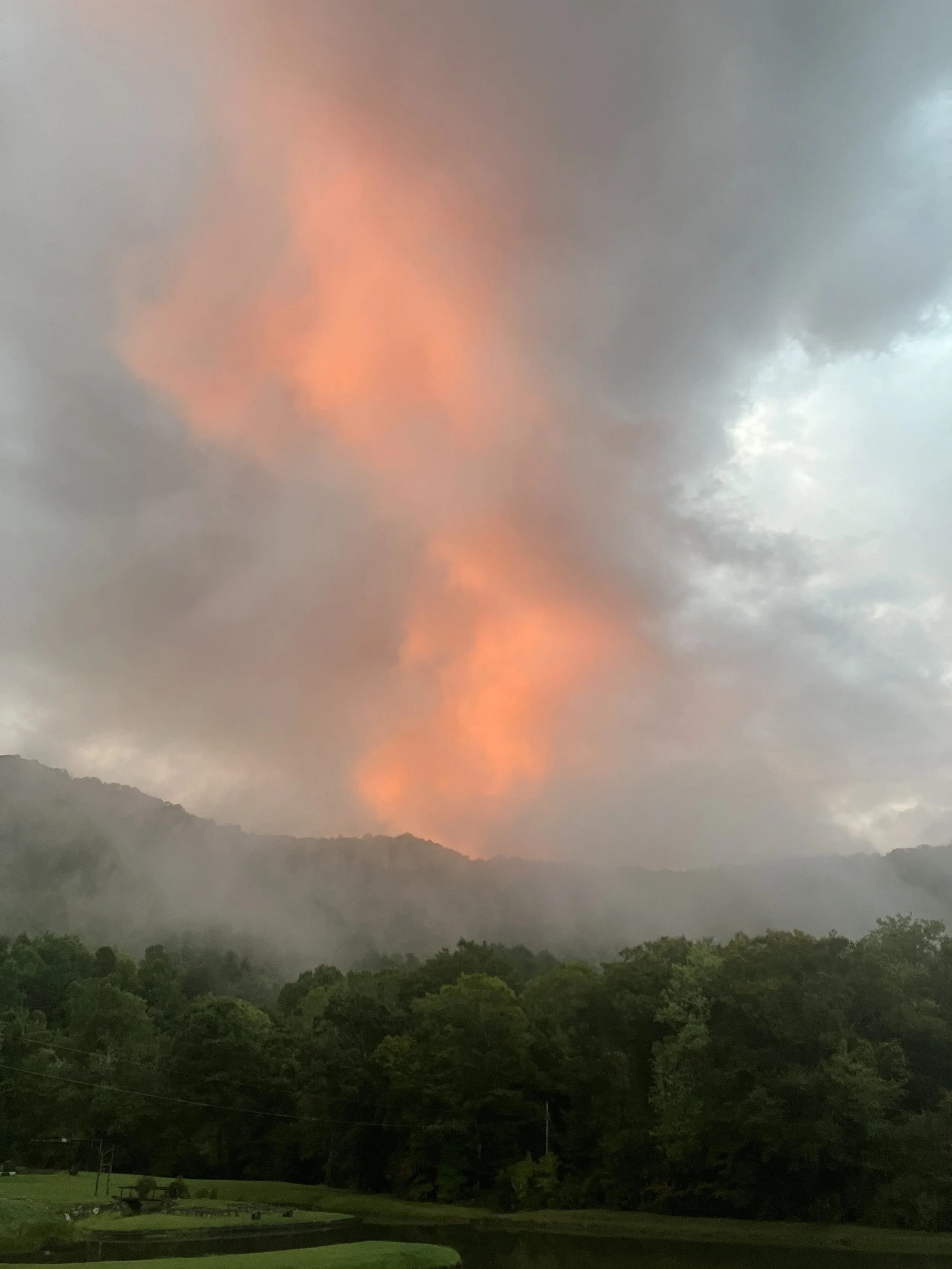 Dramatic clouds rising above the Appalachian Mountains, creating the appearance of fire in the mountains across the evening sky.