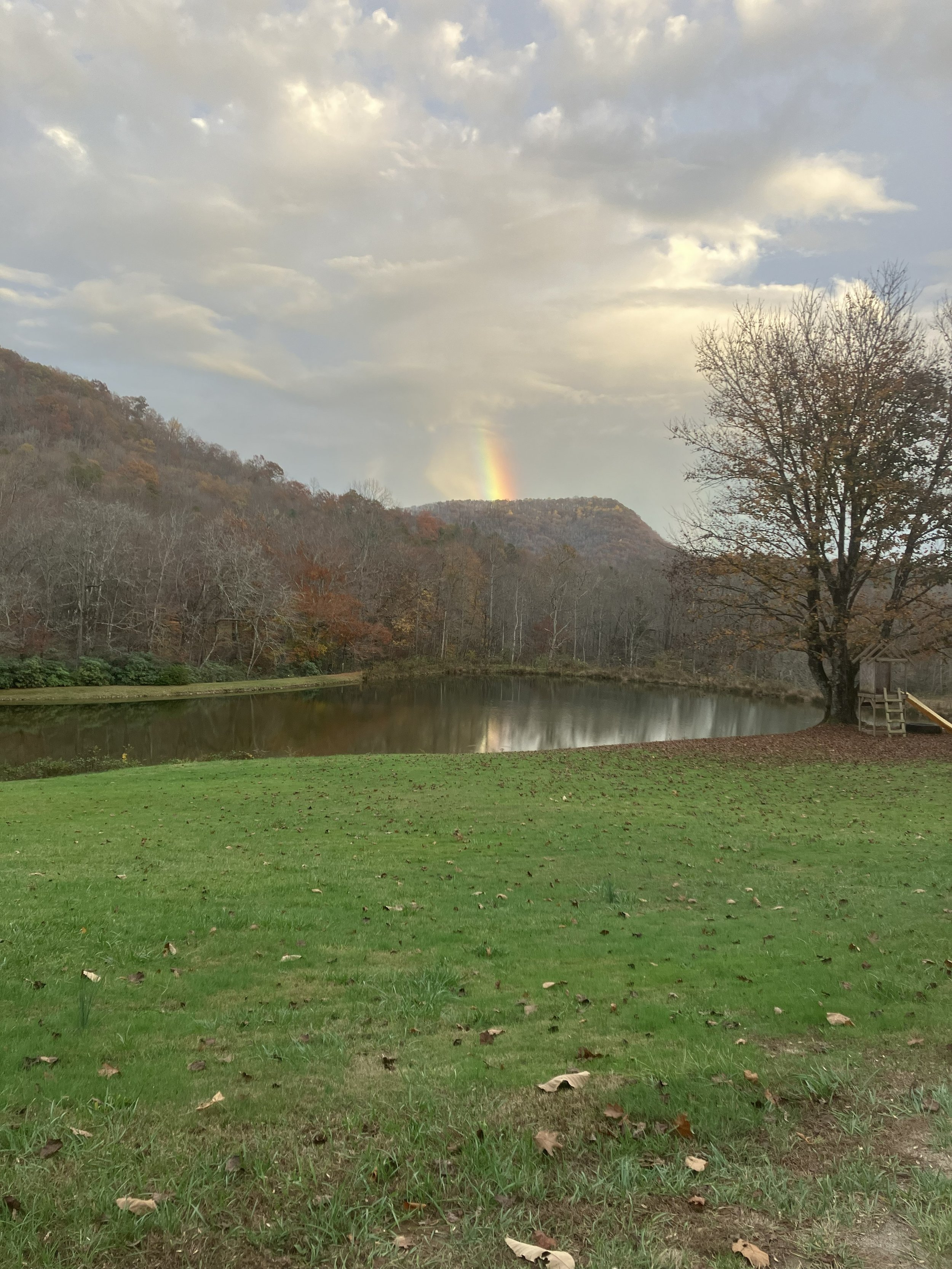 A faint rainbow appearing over a tranquil mountain pond in Western North Carolina.
