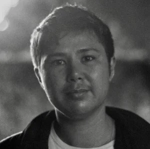 Black and white portrait of a young woman with short hair, looking into the camera with a neutral expression.
