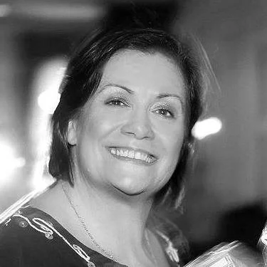 A woman with short dark hair smiling in a black and white photo.