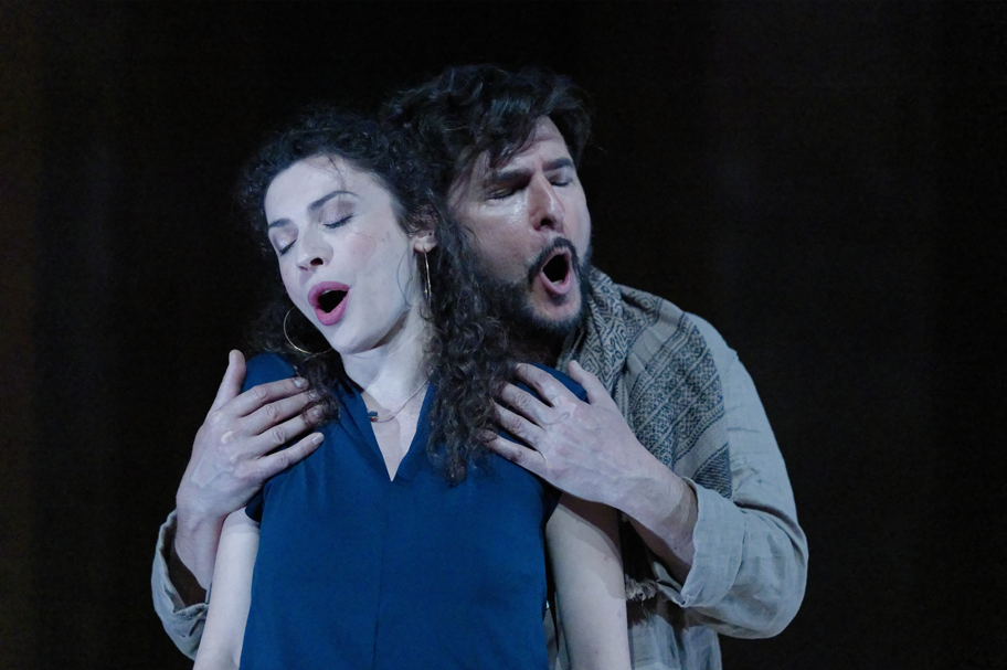 Two actors performing on stage, one woman and one man, with their eyes closed and expressive facial expressions, in a dramatic scene.
