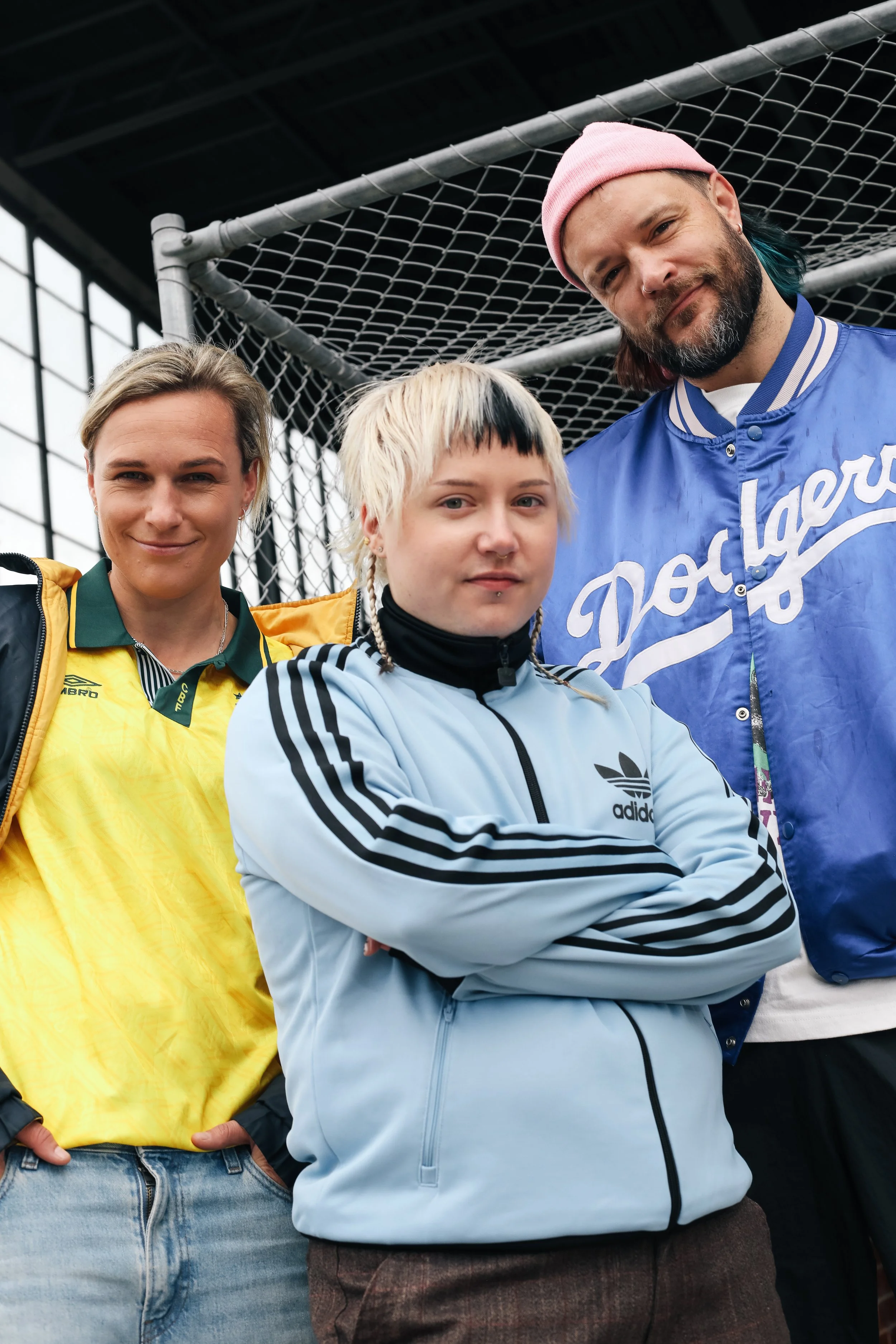 Hannah Wilkinson, Rudy Jean Rigg and Mitch Brown posed in front of a chainlink fence