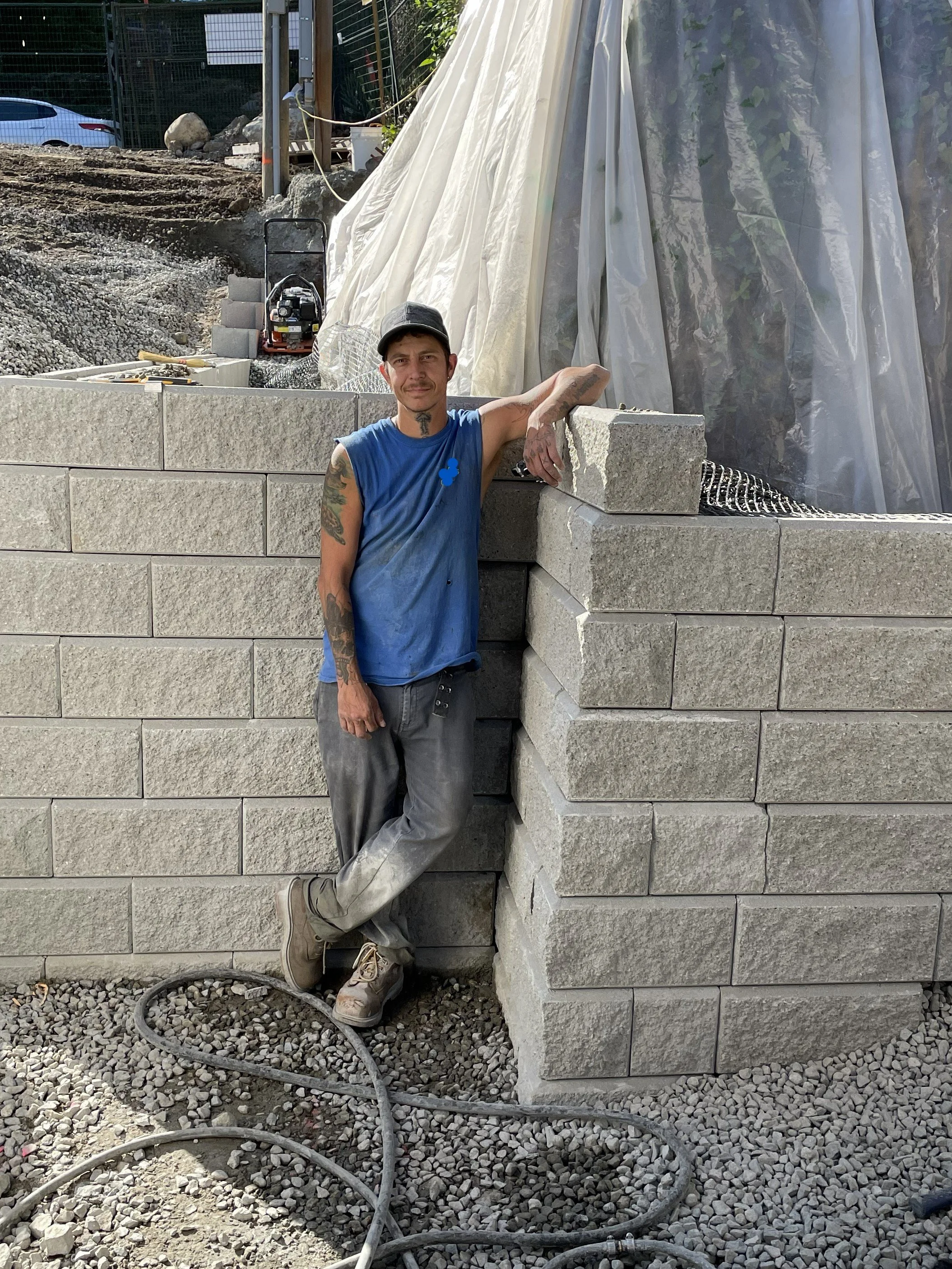 A construction worker standing against a cinder block wall at a construction site.