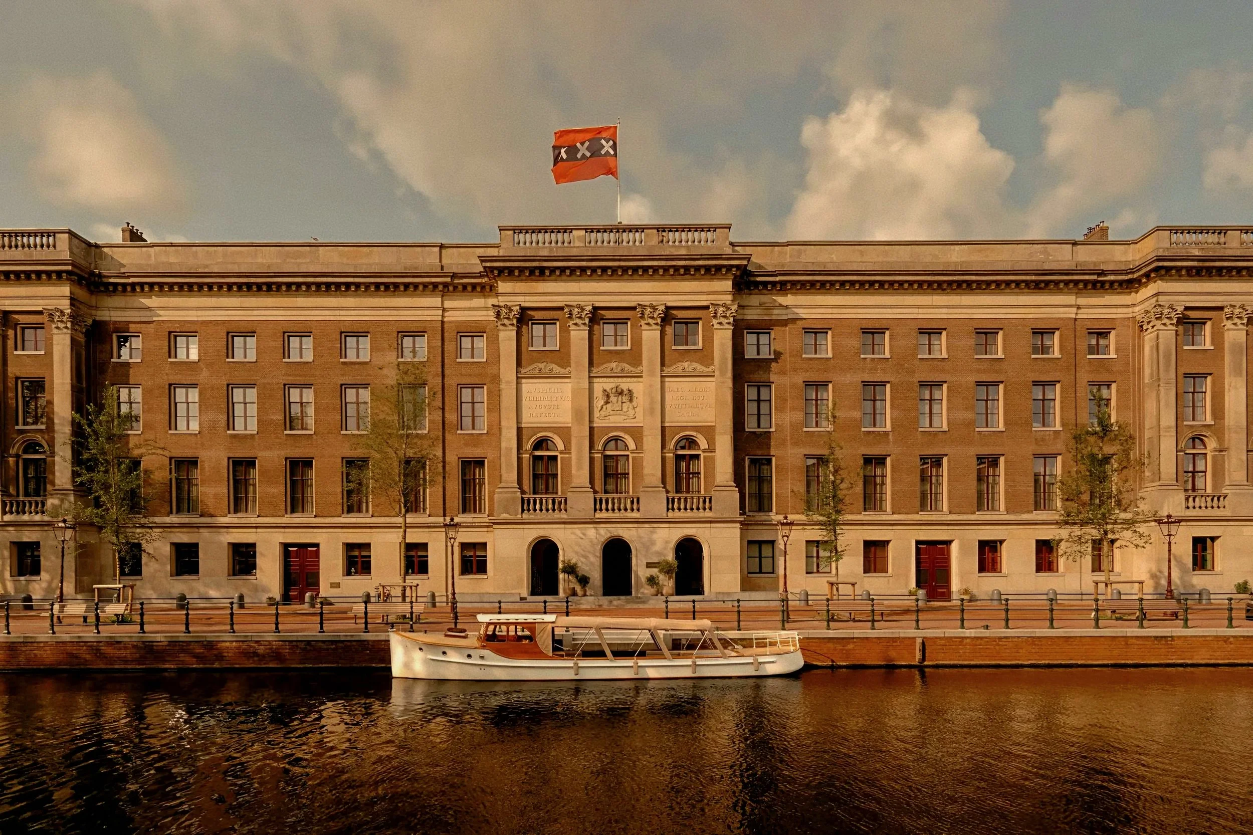 Neoclassical brick hotel exterior and mahogany boat at Rosewood Amsterdam a luxury hotel in Netherlands.