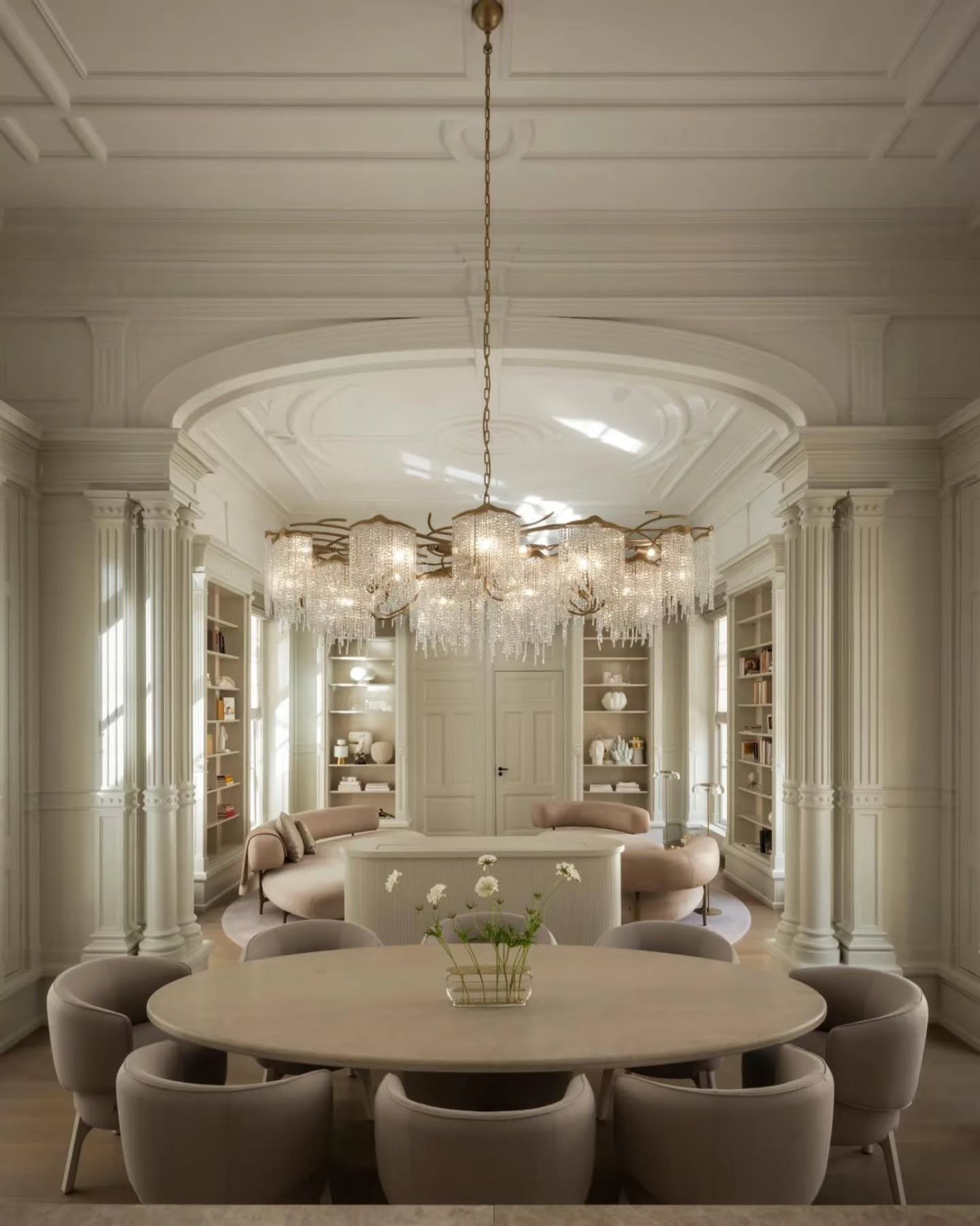 Piet Boon anchors the spatial poetry of this salon as a crystal fringe chandelier cascades through a coffered ceiling vault&mdash;anchoring fluted Corinthian pilasters, contoured mauve-blush seating, and bespoke backlit library joinery. 

​Interior D