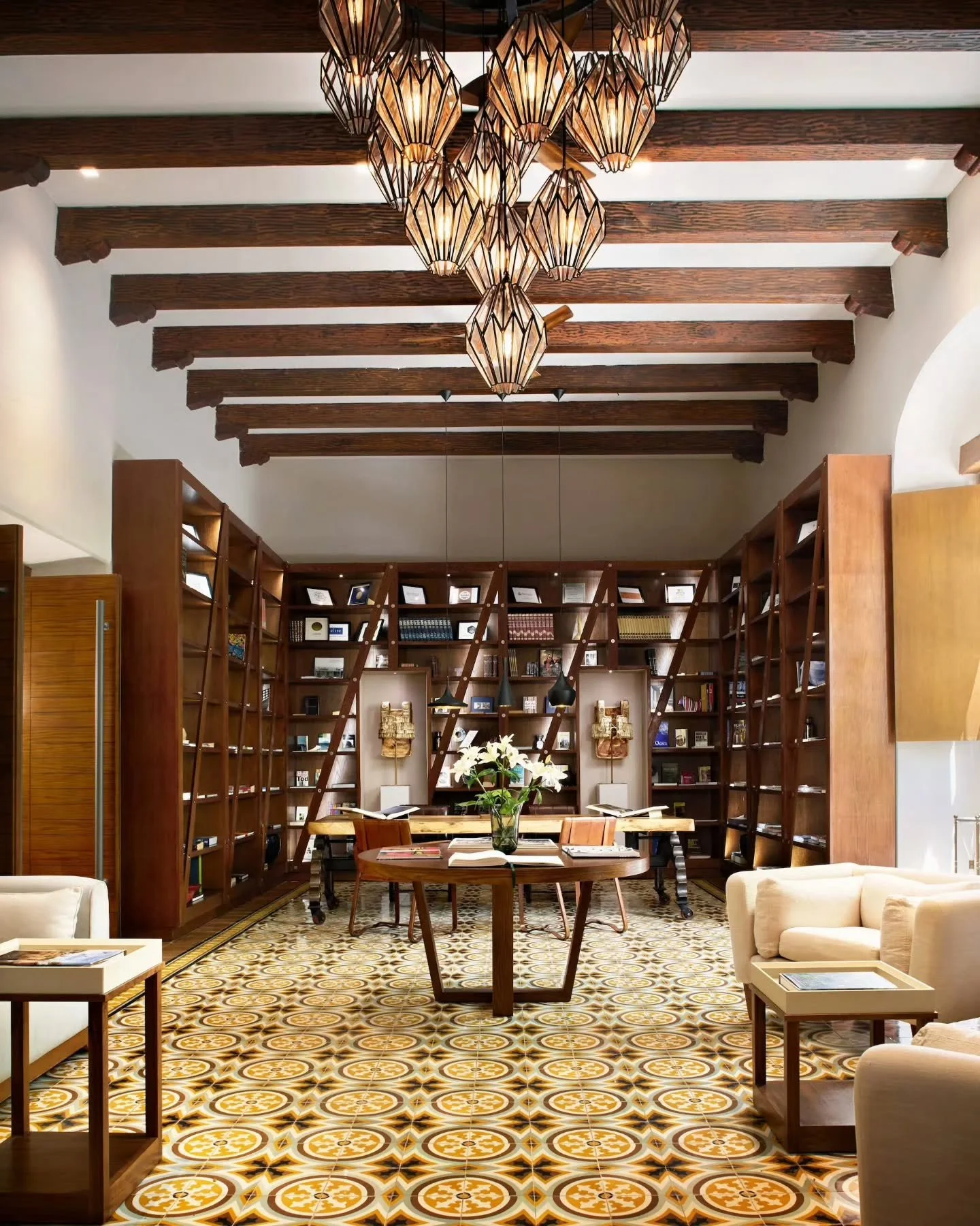Intricate mustard and cream pasta tile flooring anchors a soaring library vault&mdash;framed by bespoke mahogany bookcases, low ivory armchairs, and a sculptural geometric lantern installation.

​Interior Design by Paulina Mor&aacute;n.

​Casa Princi