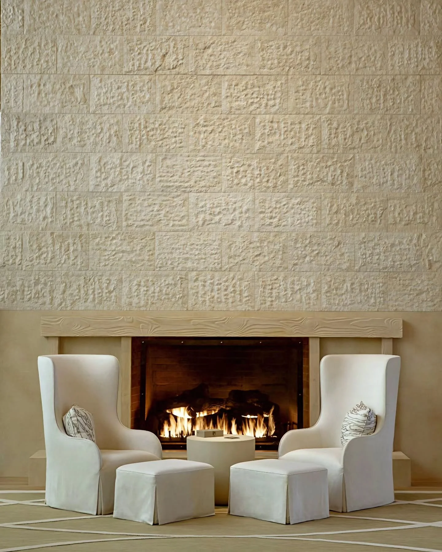 ​Textured ashlar stone cladding creates a dramatic backdrop for a central hearth aperture, flanked in precise symmetry by upholstered armchairs and a low sculptural stone cylinder.

​Interior Design by Todd-Avery Lenahan.

​The Great Hall at @sensei
