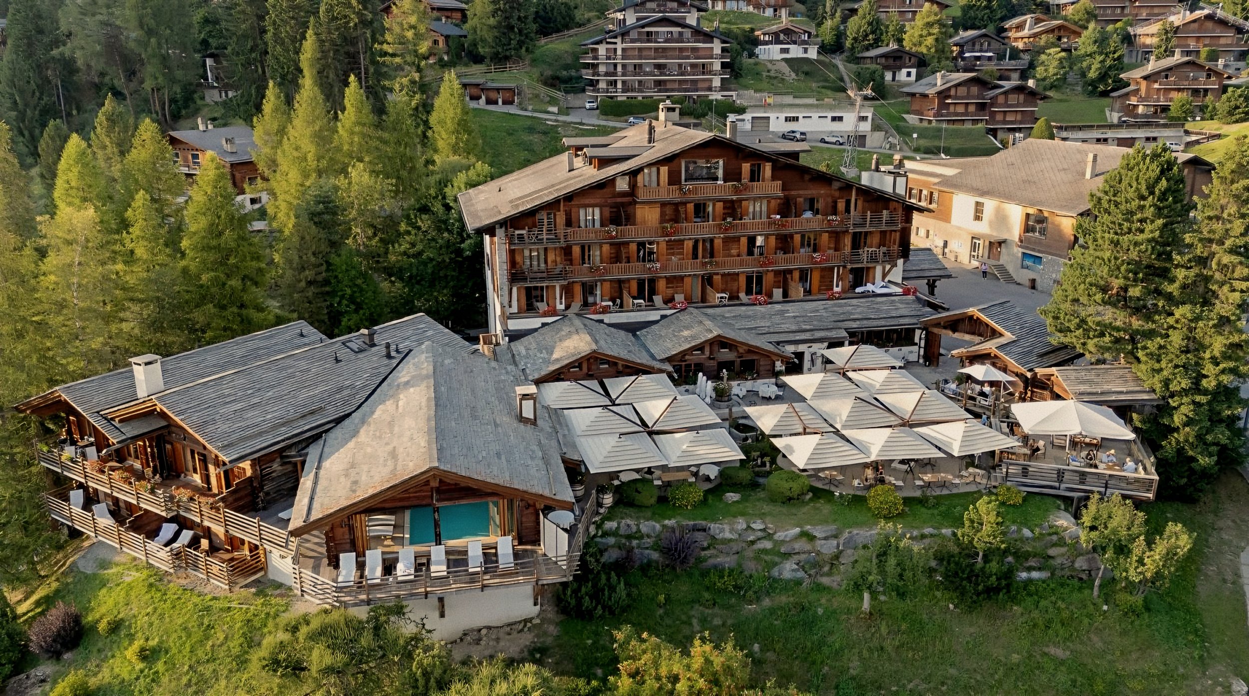 Chalet exterior aerial view in forest at Le Chalet d’Adrien Luxury Swiss Alps in Verbier, Valais, Switzerland.