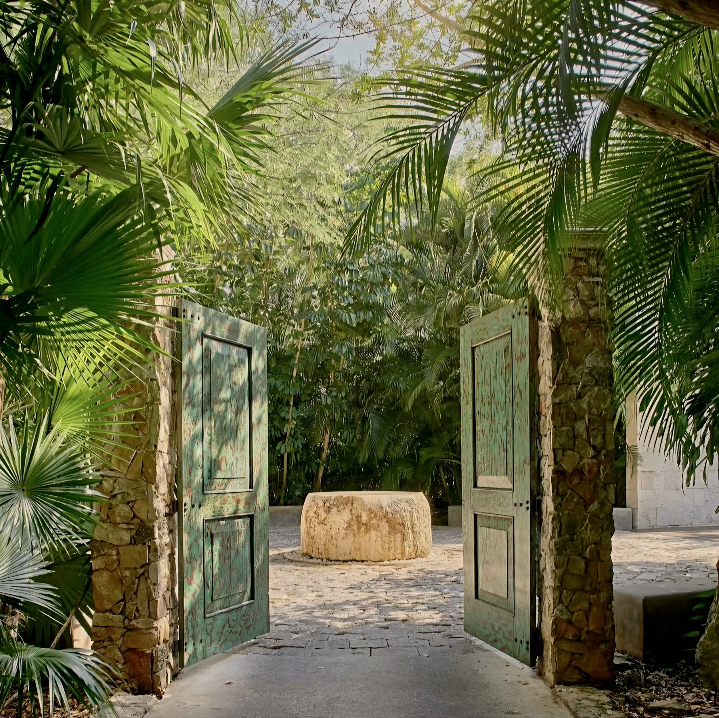 Distressed teal wooden courtyard gates and palms at Hacienda Chablé Yucatán, Chocholá, Mexico.