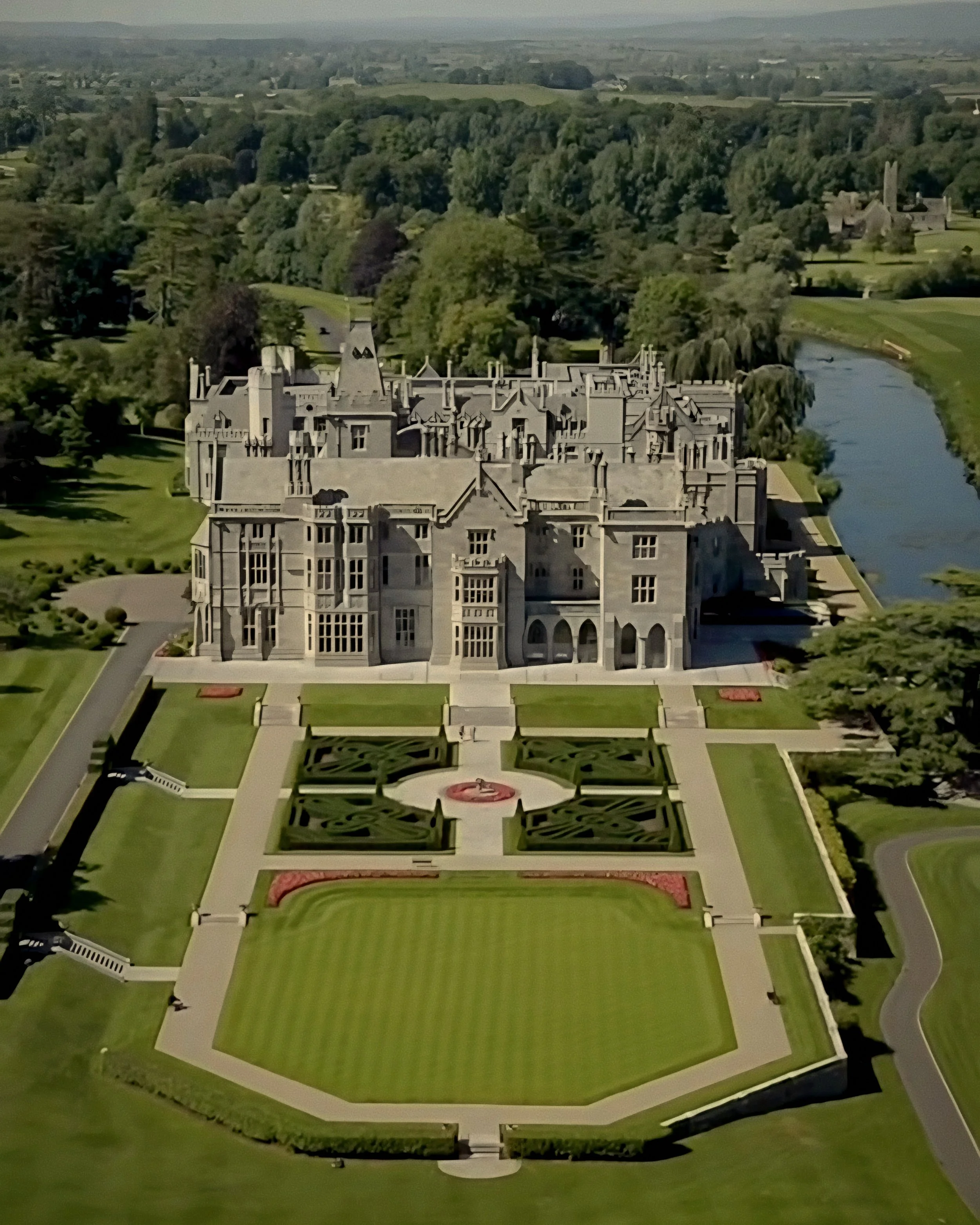 Gothic limestone manor facade and parterre garden exterior at Adare Manor luxury hotel in Ireland.