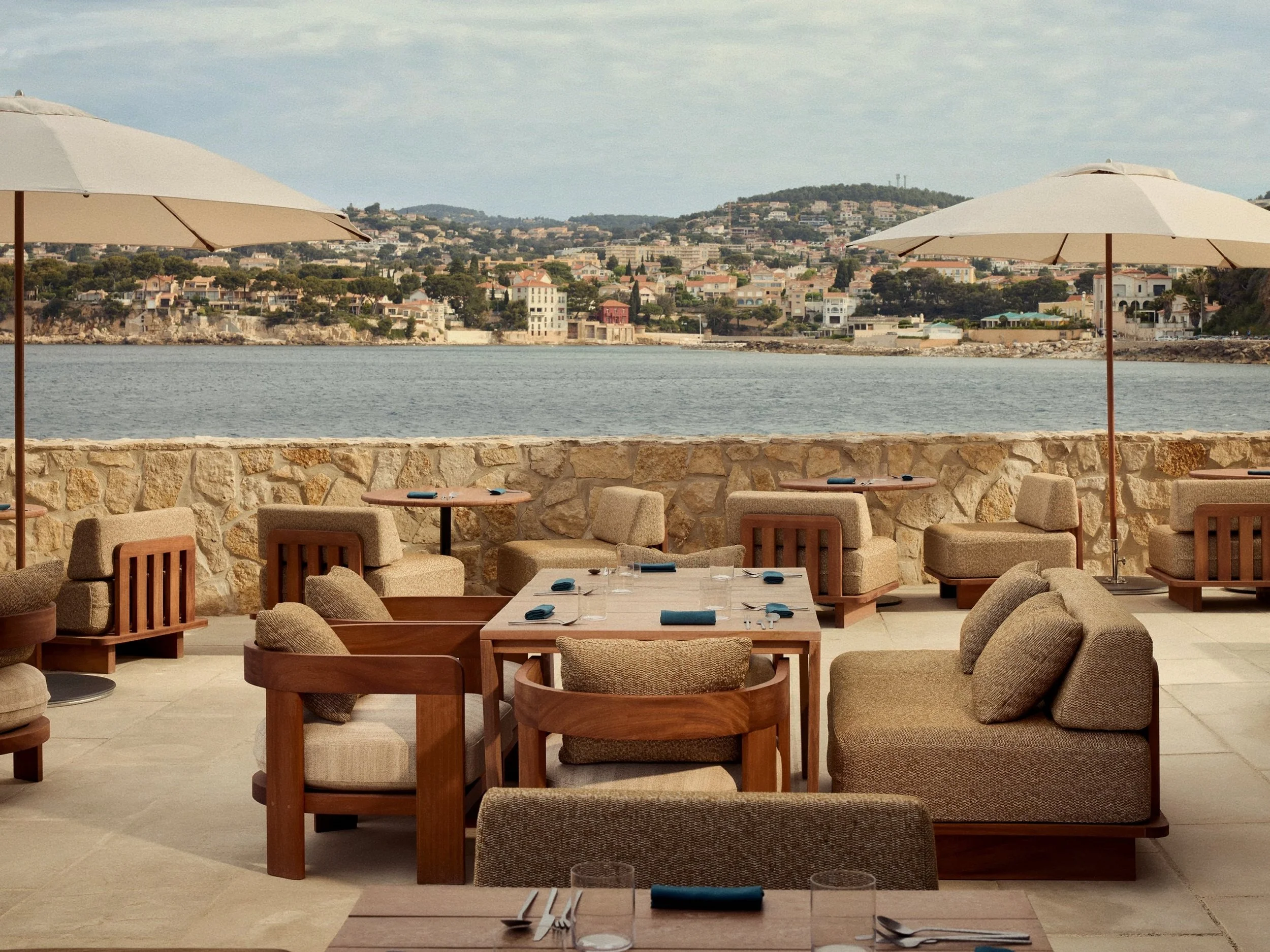 Oceanfront dining terrace with wooden seating overlooking Bandol Bay on the French Riviera.
