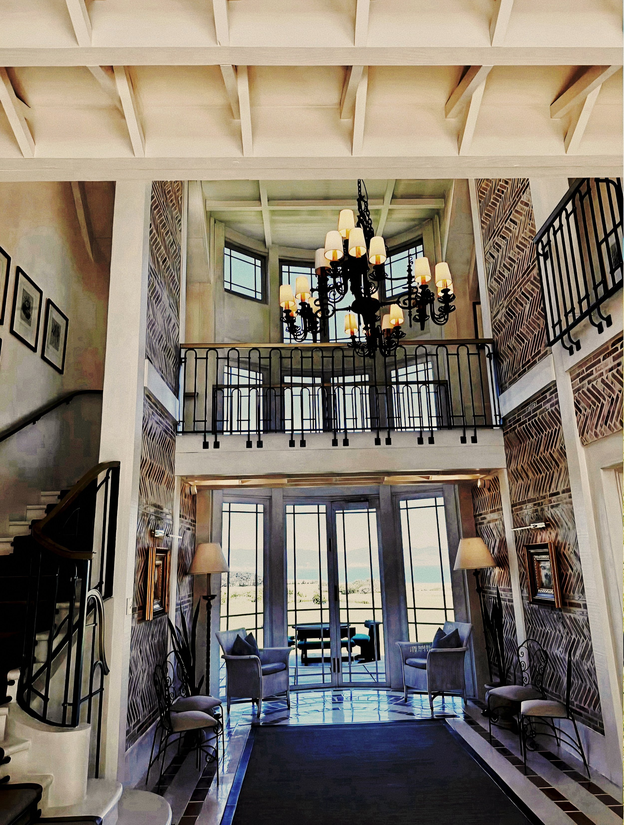 Double-height entrance gallery with grand chandelier and coastal views at Wharekauhau Country Estate, New Zealand.