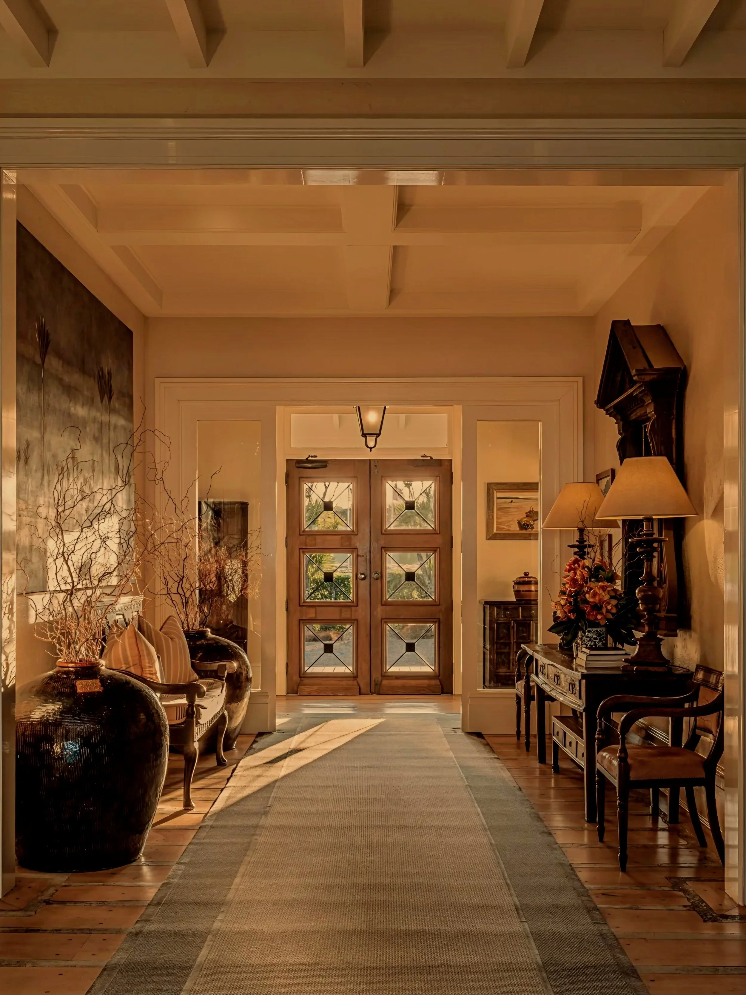 A masterfully appointed estate foyer featuring a sweeping runner, classical glass-paned double doors, and warm ambient lighting. This sophisticated architectural entryway represents the global contact portal for ROYAUME luxury editorial and press inq