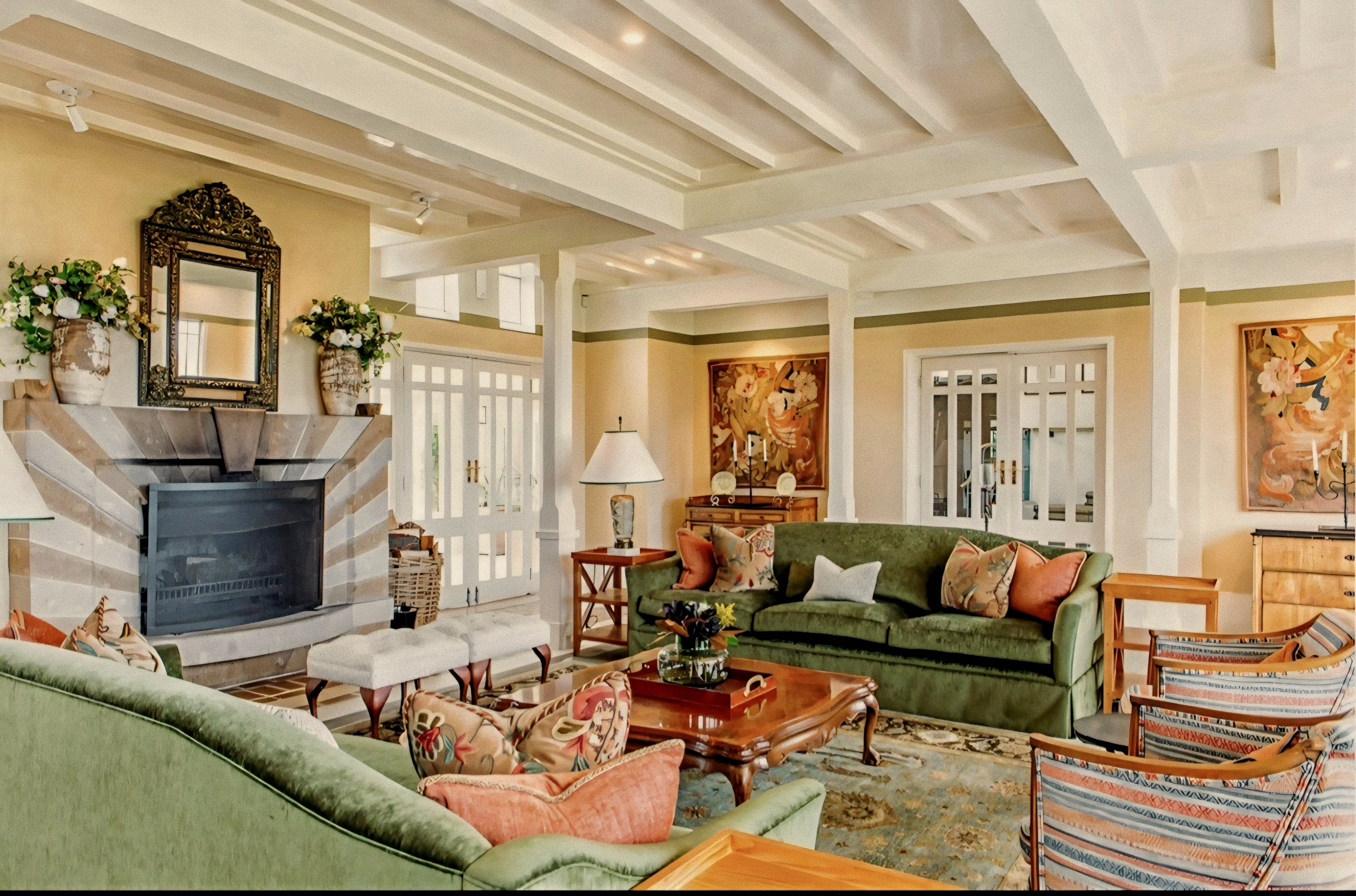 Main salon with stone fireplace and olive velvet sofas by Virginia Fisher at Wharekauhau Country Estate, New Zealand.