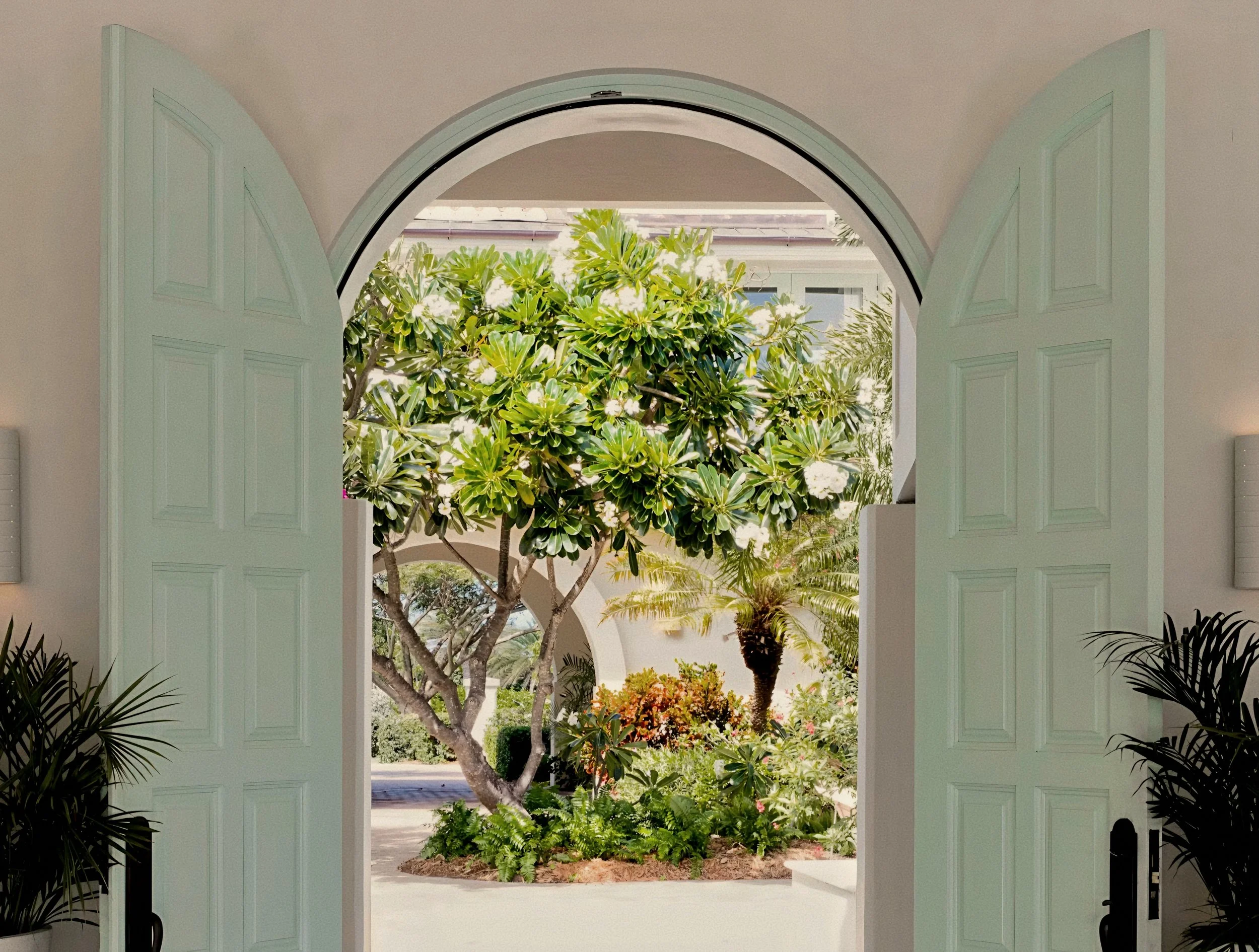 Arched estate entrance framing tropical foliage at Jumby Bay luxury private island, Antigua.