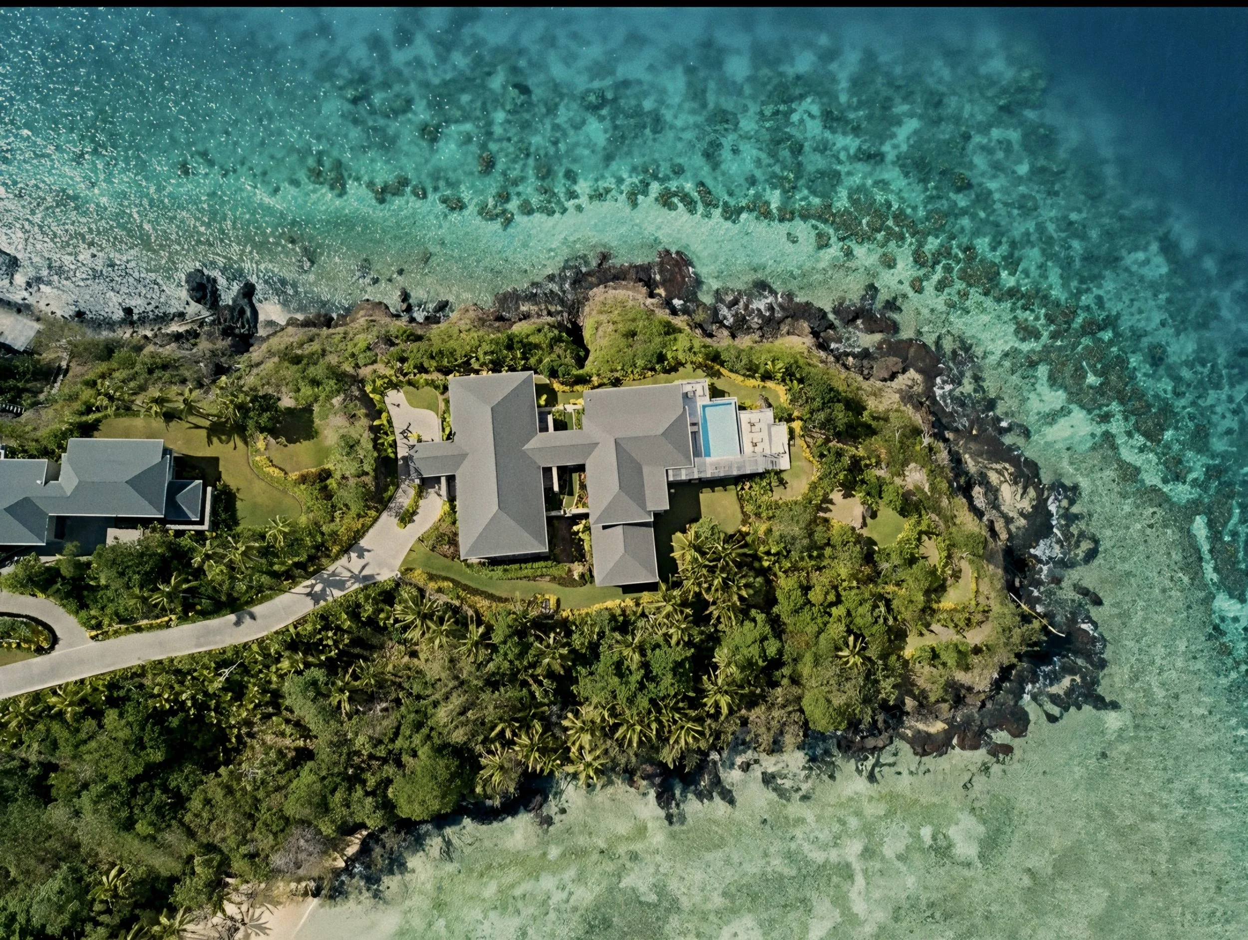 Aerial view of a hilltop villa perched above the Great Astrolabe Reef at Kokomo Private Island, Fiji.