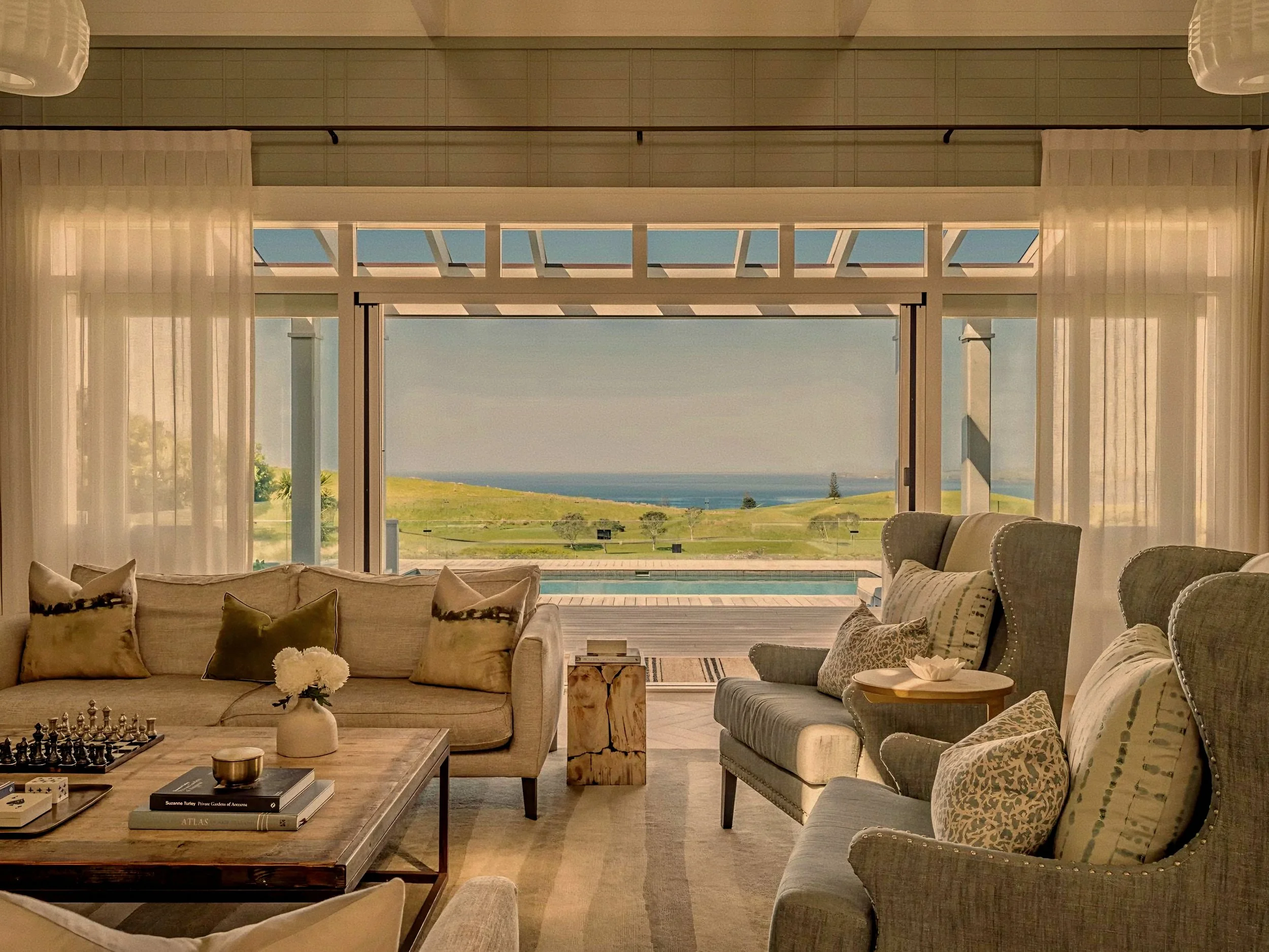Oceanfront living room framed by glass doors at Rosewood Kauri Cliffs, Matauri Bay, New Zealand.