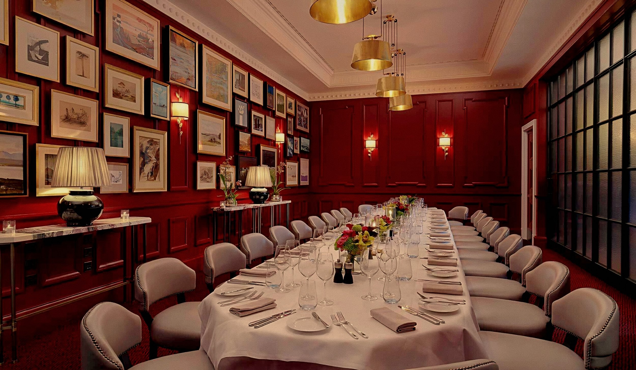 Crimson paneled walls and long table dining salon at Adare Manor luxury hotel in Ireland.