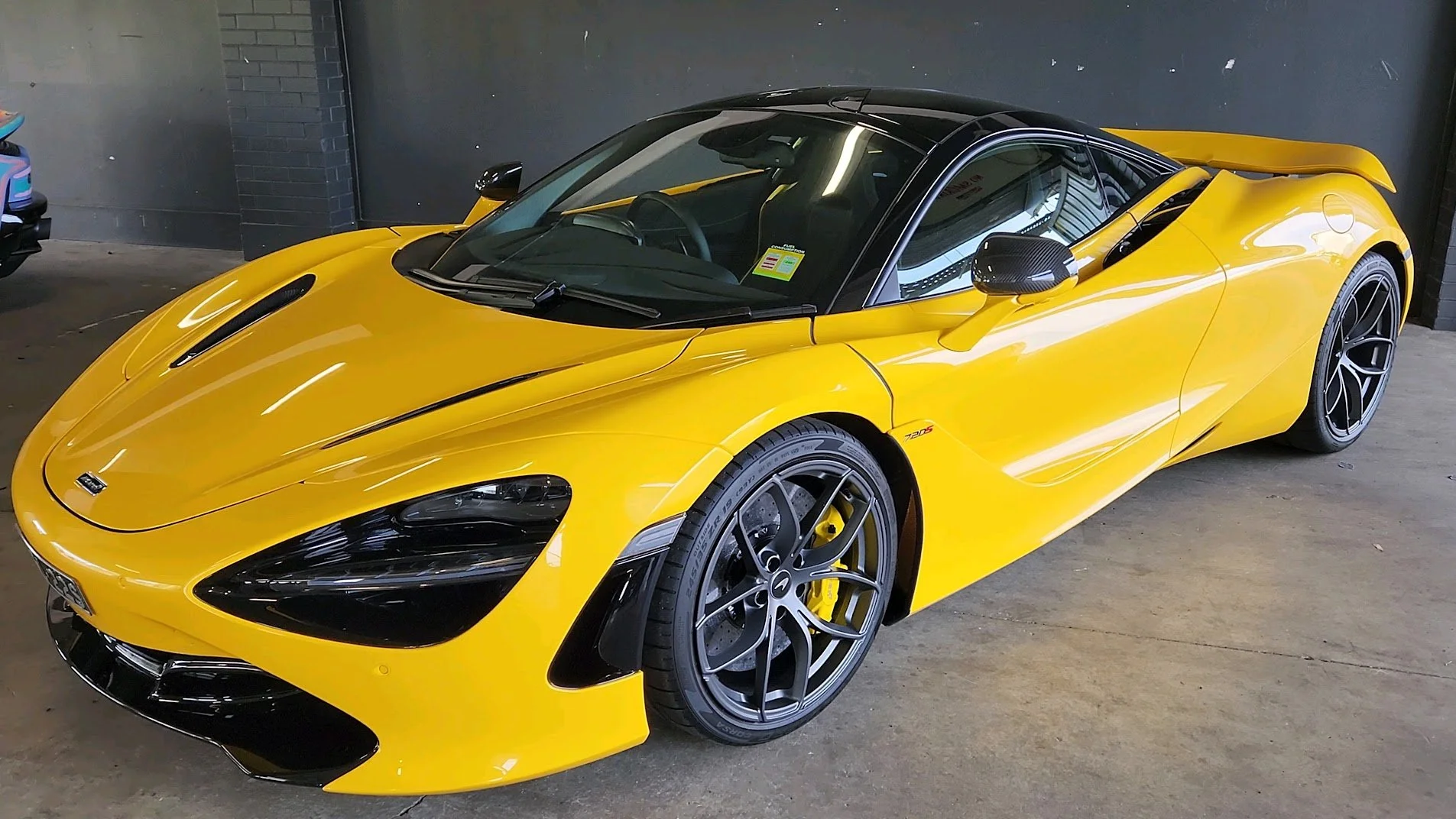 Yellow sports car with black accents parked inside a garage.