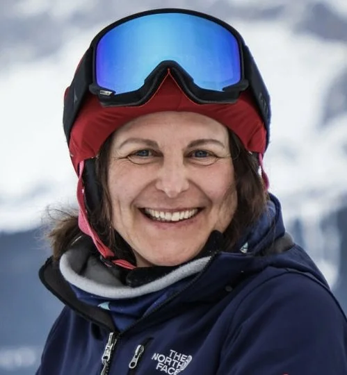 Frau in Wintersport-Ausrüstung, trägt Skihelm und Skibrille, steht im Schnee.