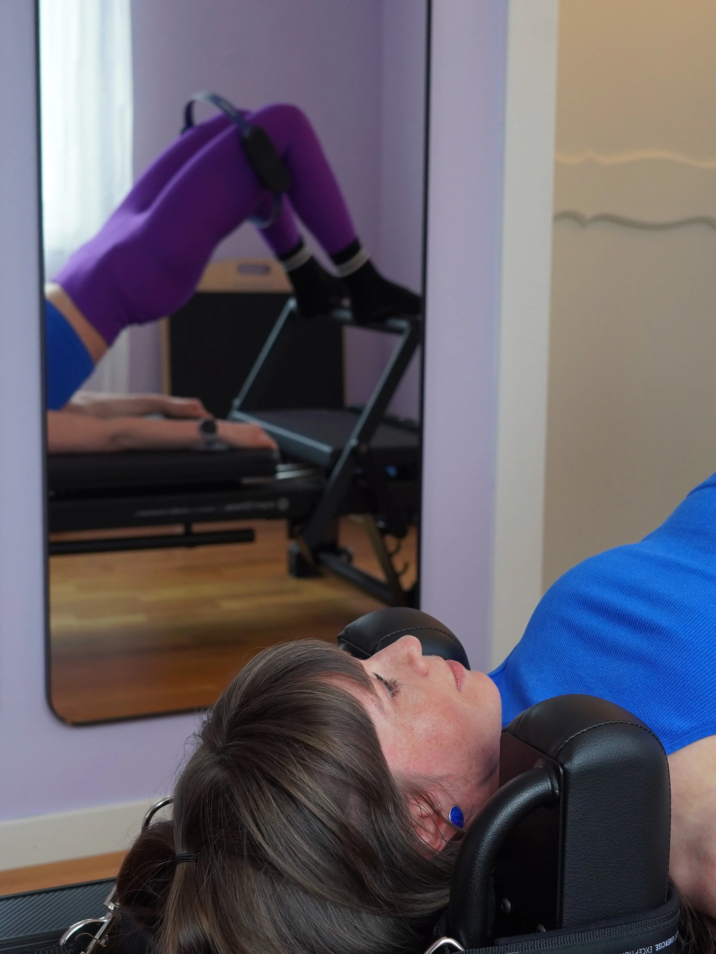 Woman on a Pilates Reformer feet on footbar and legs in Magic Circle