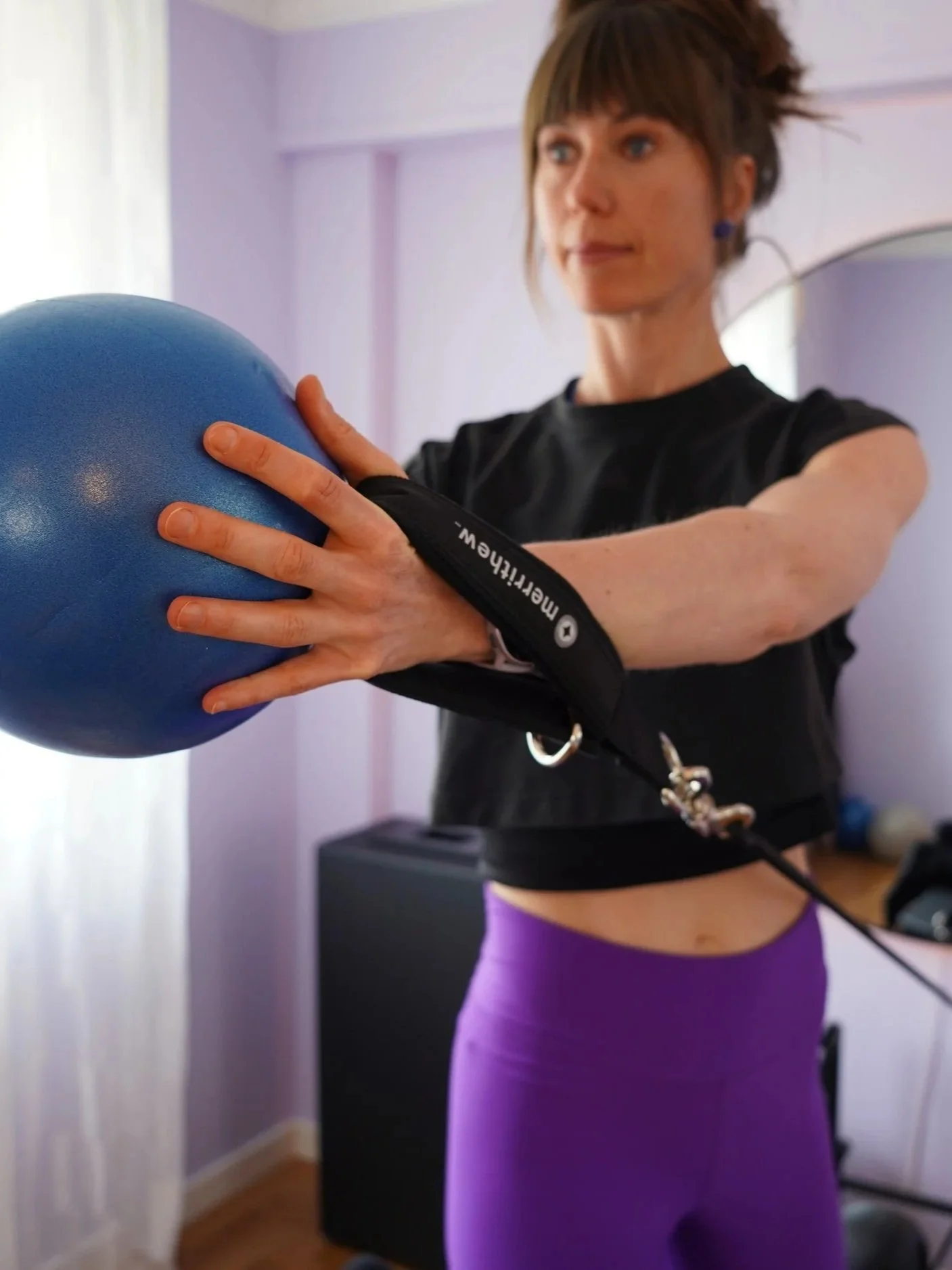 Woman on a Pilates Reformer holding a stability ball