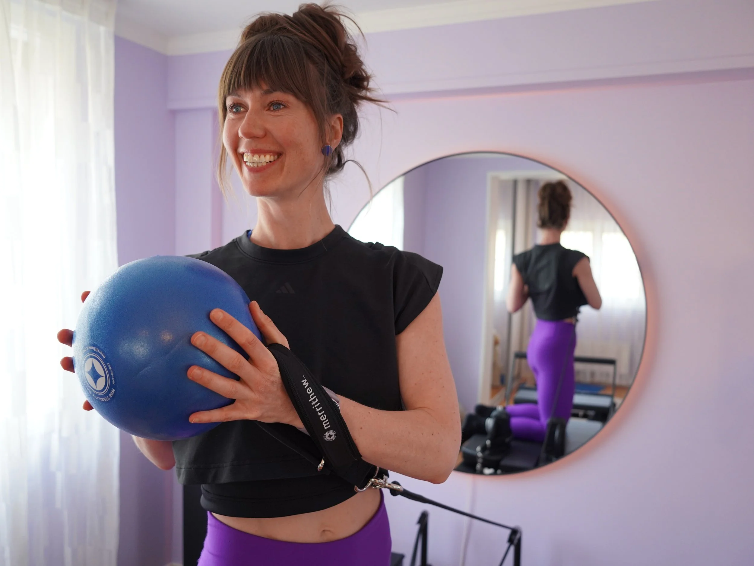 Woman on a Pilates Reformer holding a stability ball